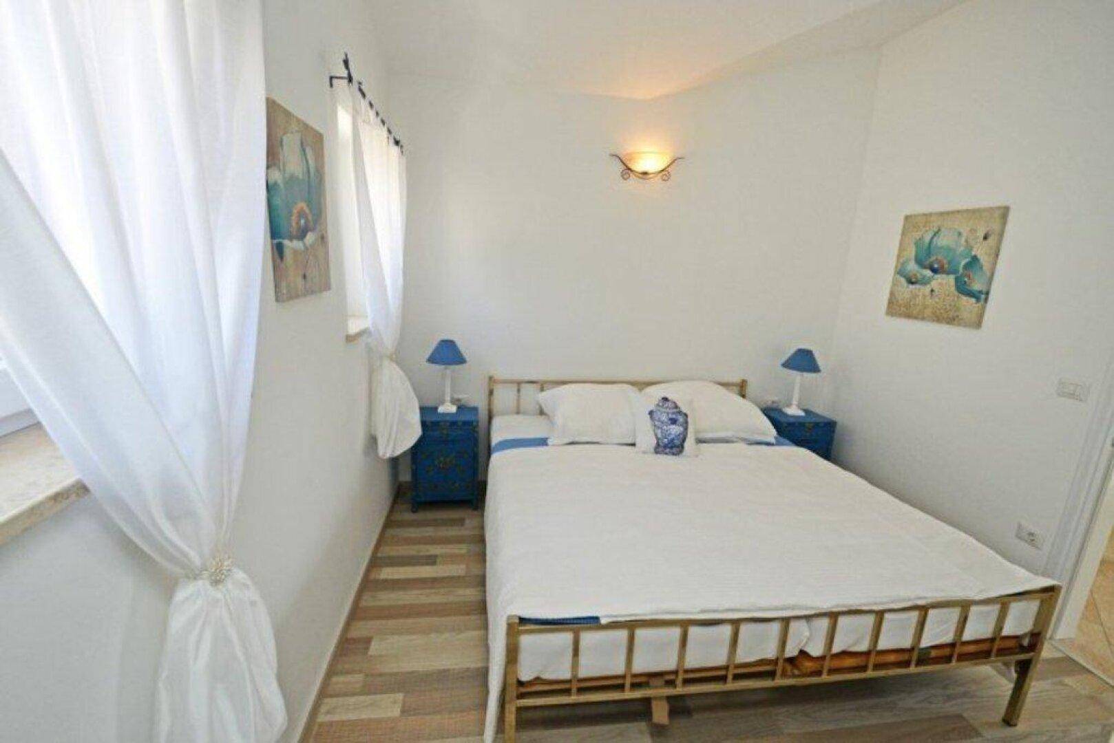 Gemütliches Schlafzimmer mit Doppelbett, Holzboden und blauen Nachttischen.