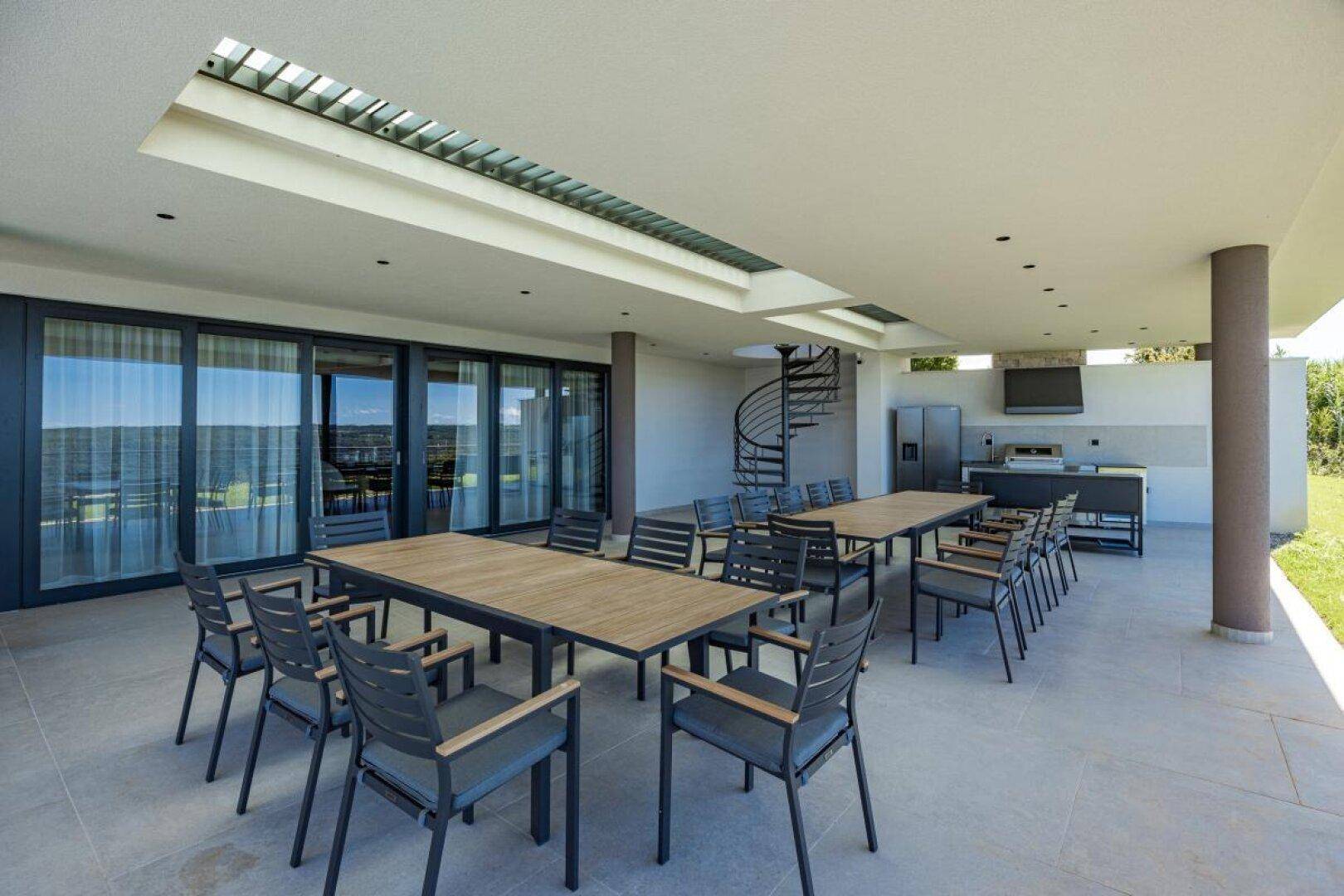 Geräumige überdachte Terrasse mit Essbereich und moderner Außenküche für gesellige Abende.