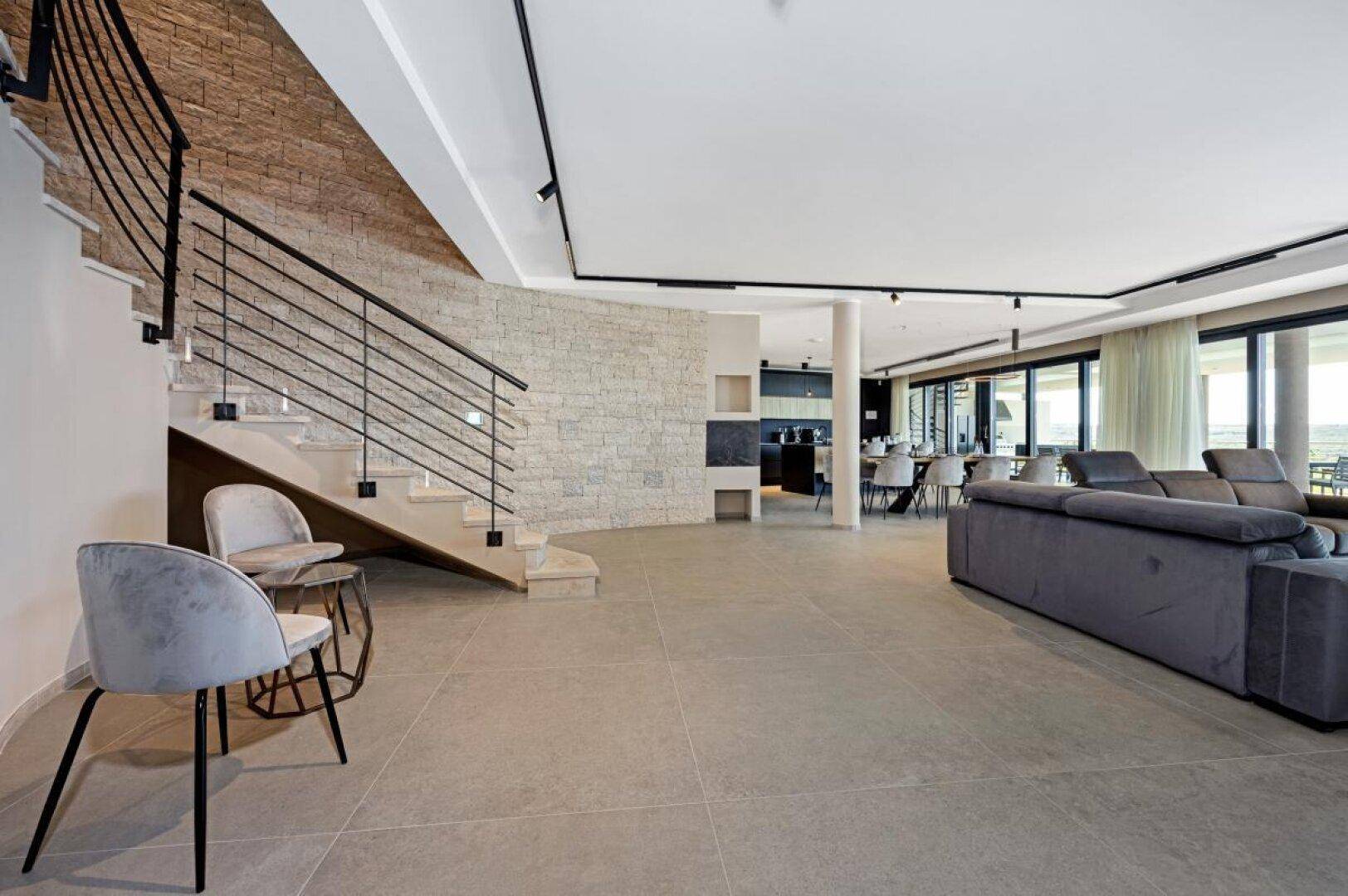 Geräumiges Wohnzimmer mit Steintreppe, Fliesenboden und Blick auf die Landschaft.
