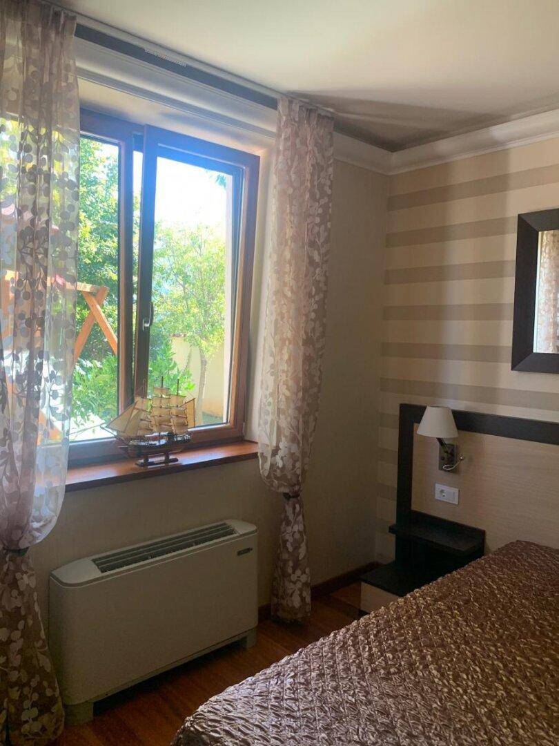 Schlafzimmer mit Fenster, das viel Tageslicht hereinlässt und Blick ins Grüne bietet.