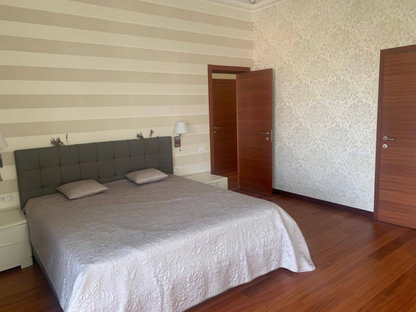 Geräumiges Schlafzimmer mit Doppelbett, Holzboden und zwei Holztüren.