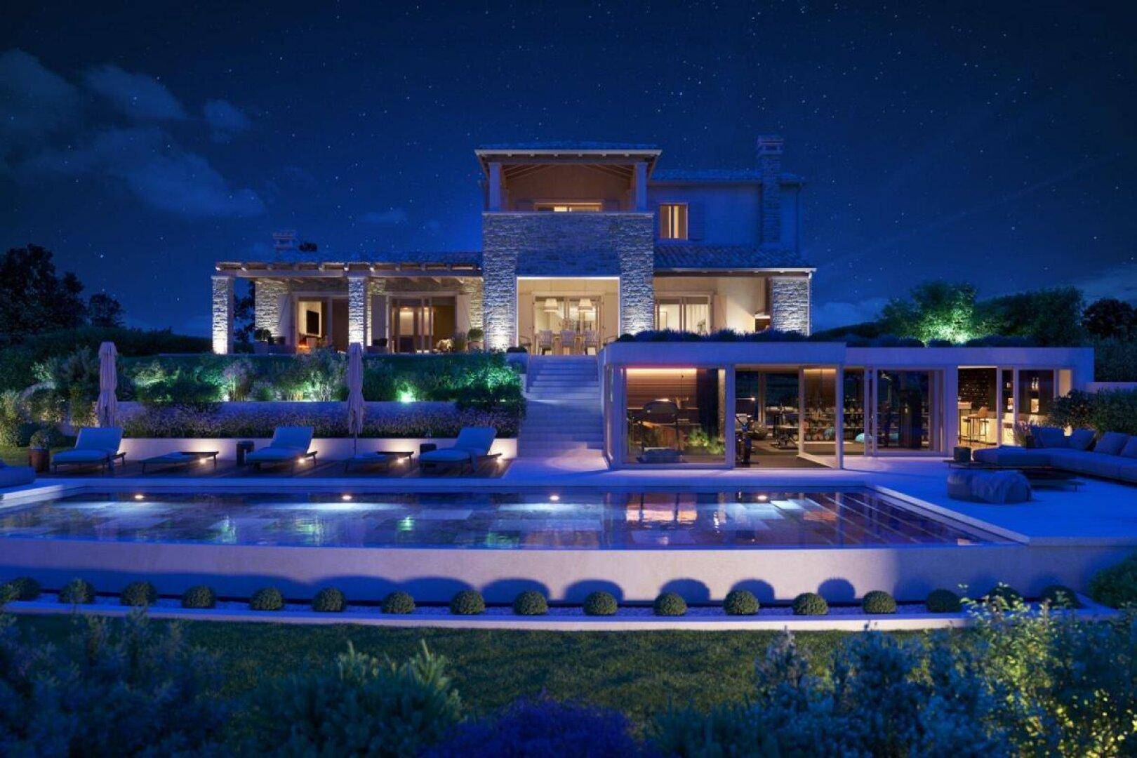 Beleuchtete Luxusvilla bei Nacht mit großem Poolbereich und stimmungsvoller Außenbeleuchtung unter sternenklarem Himmel.