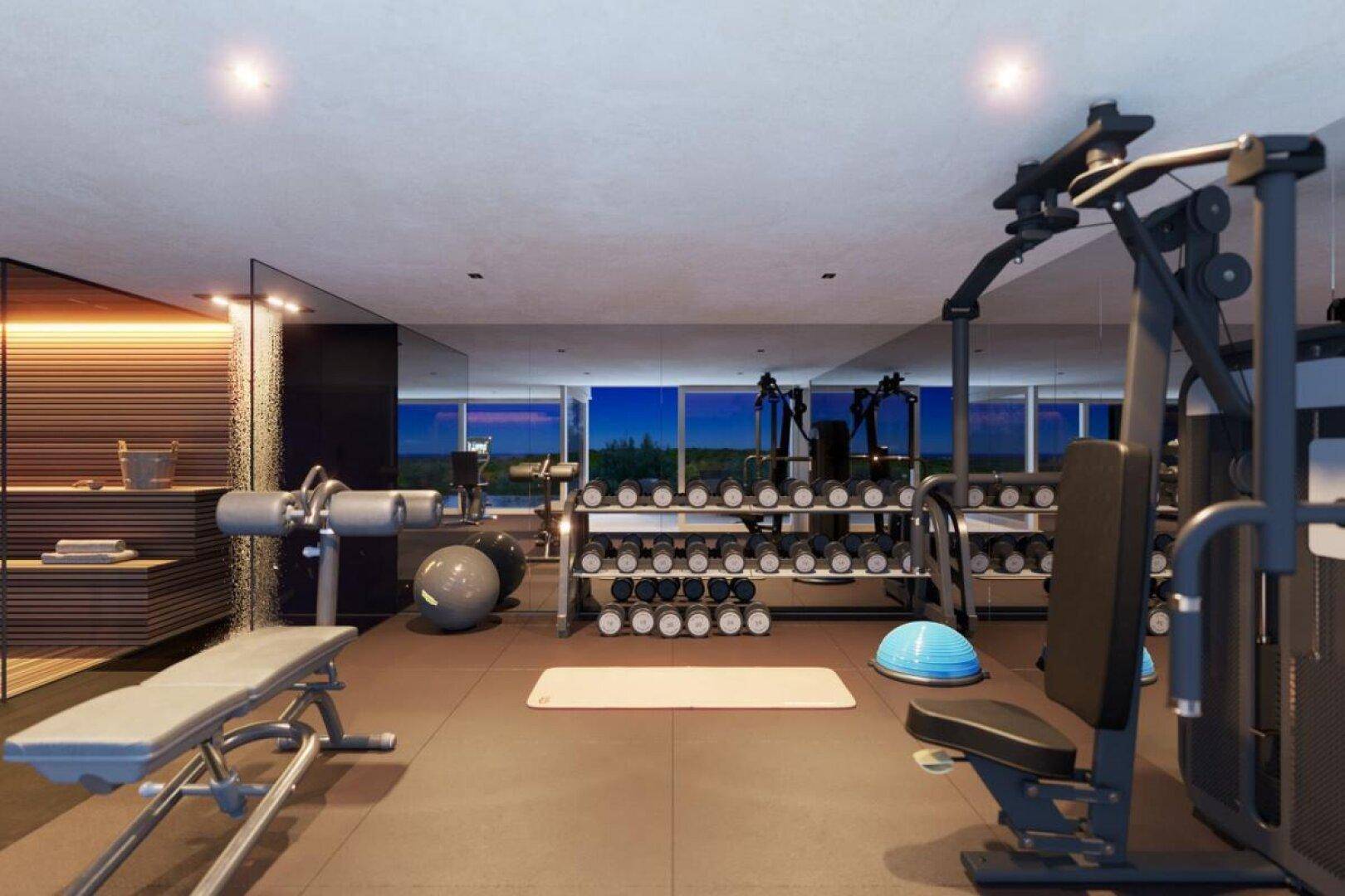 Geräumiger Fitnessraum mit einer Vielzahl von Trainingsgeräten und Blick auf die Außenlandschaft.
