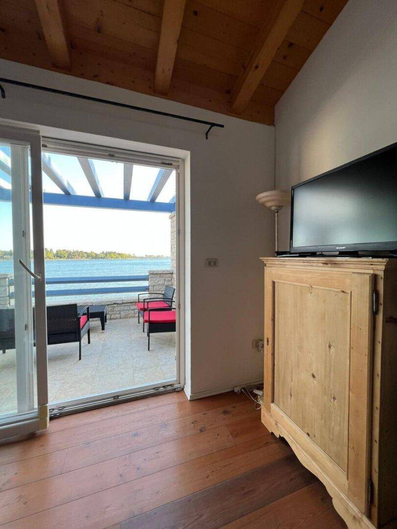 Gemütlicher Wohnbereich mit Holzbalkendecke und direktem Zugang zur Meerblick-Terrasse.