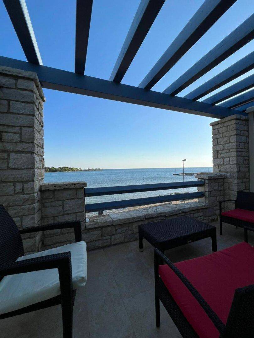 Möblierte Terrasse mit Meerblick und Pergola, ideal für entspannte Stunden im Freien.