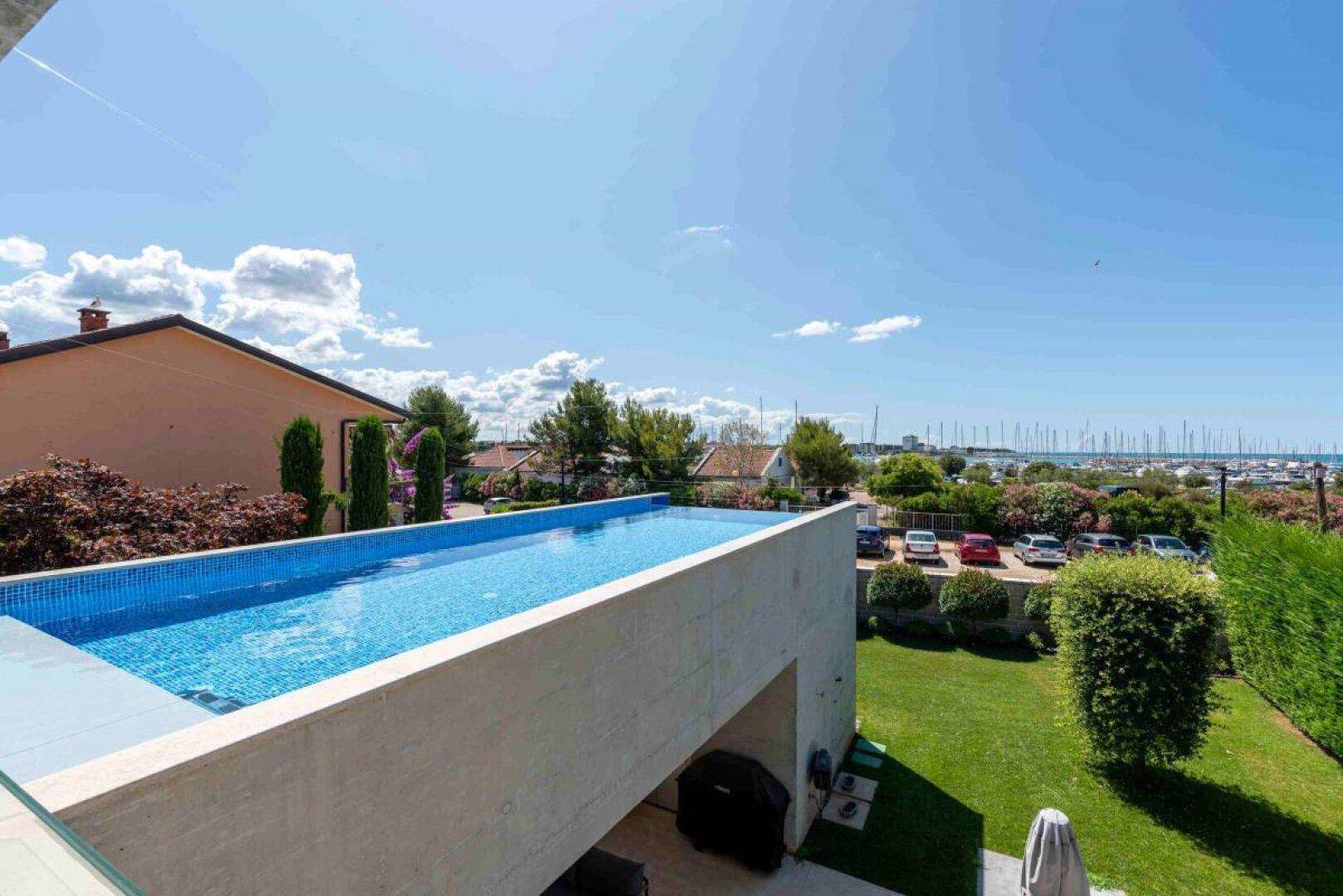 Außenansicht des Hauses mit Infinity-Pool und Blick auf die umliegende Landschaft und das Meer.