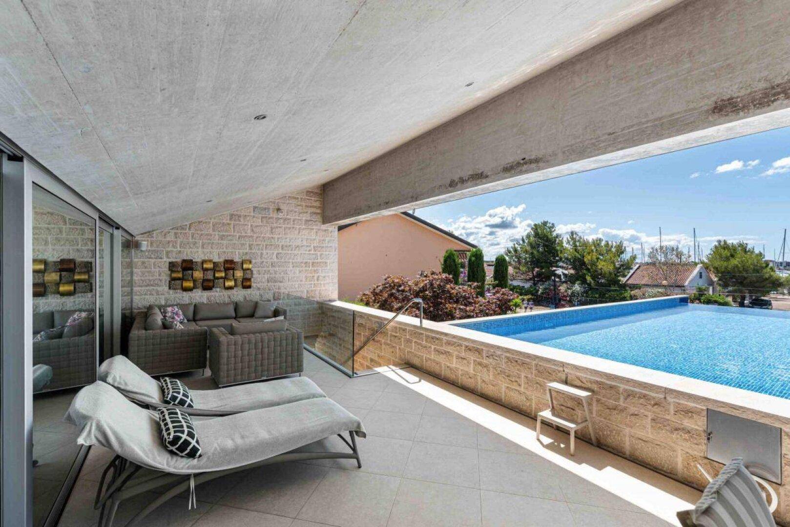 Elegante Terrasse mit bequemen Lounge-Möbeln und direktem Zugang zum Infinity-Pool mit Meerblick.