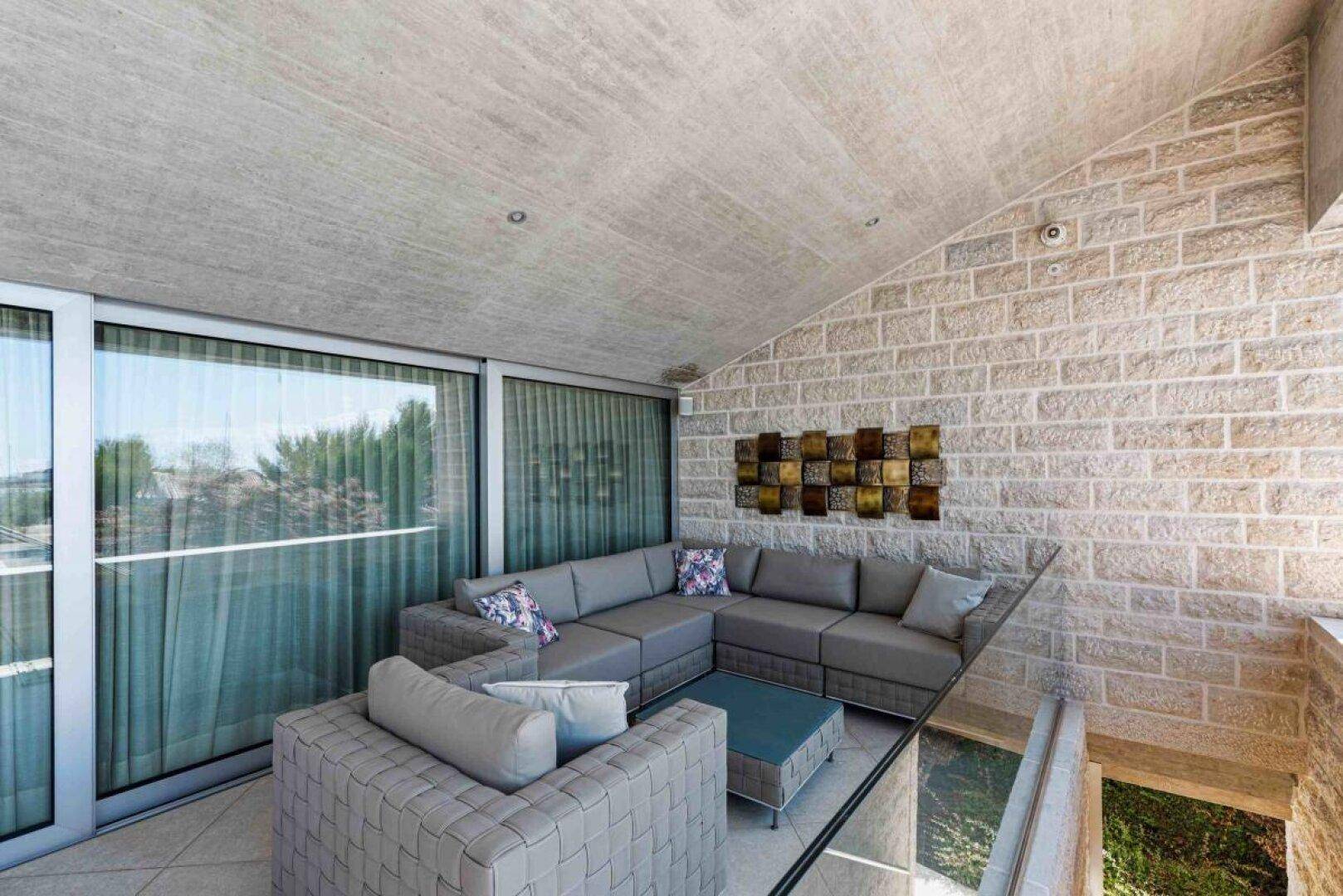 Gemütlicher Lounge-Bereich mit modernen Sofas und Blick auf den Garten und das Meer.