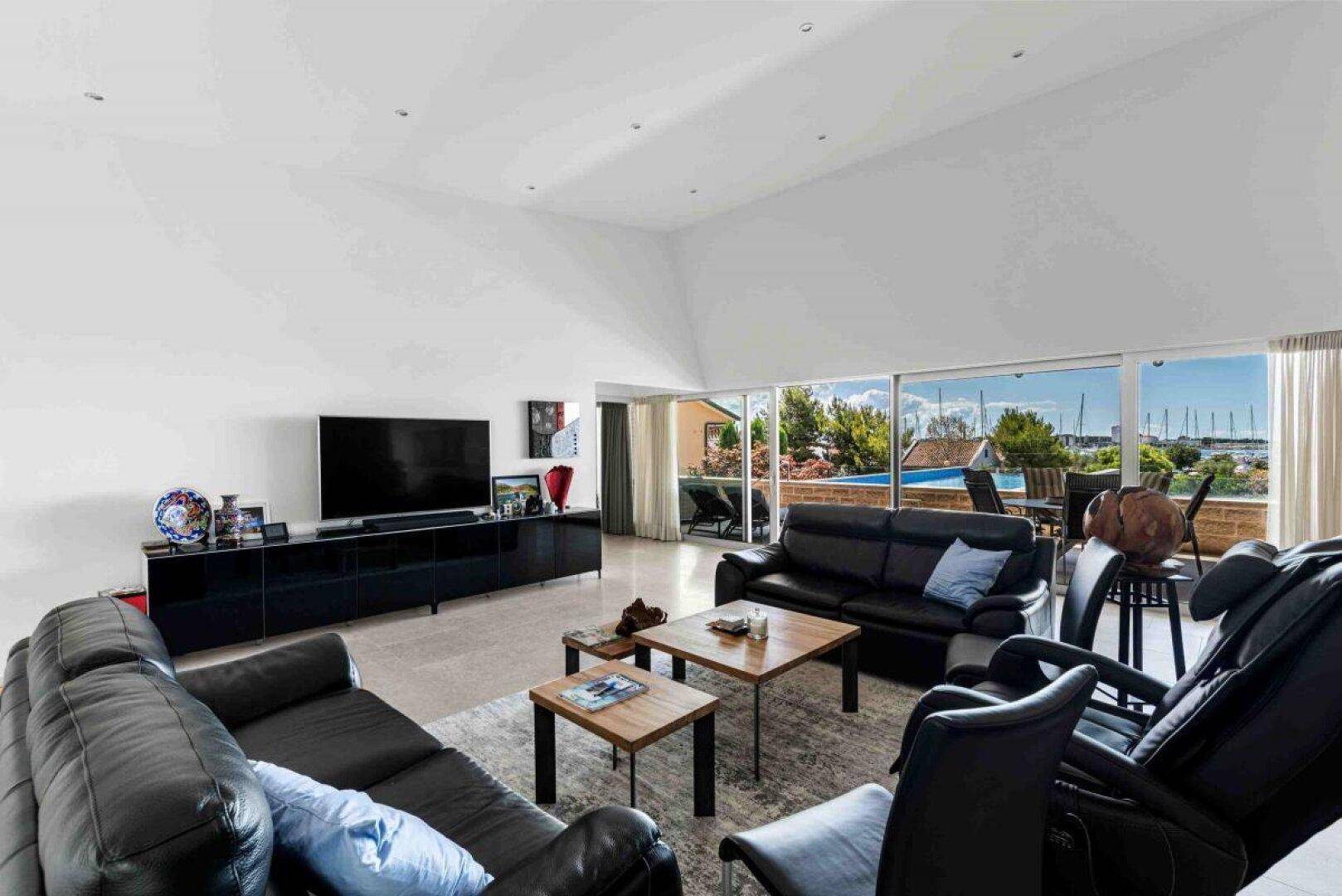 Modernes Wohnzimmer mit bequemen Ledersofas, Holztischen und Panoramablick auf das Meer.