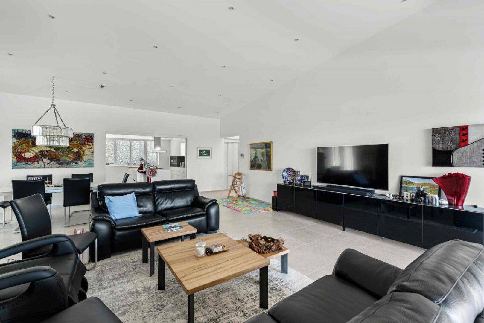 Offener Wohn- und Essbereich mit Ledersofas, Esstisch und Blick in die moderne Küche.
