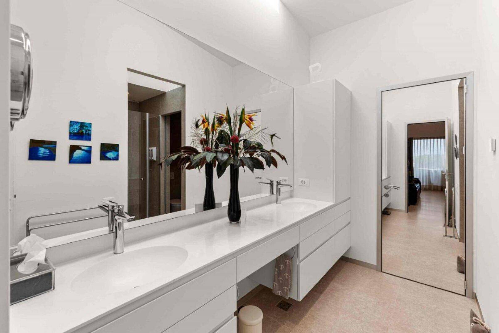 Modernes Badezimmer mit Doppelwaschbecken, großem Spiegel und minimalistischem Design.