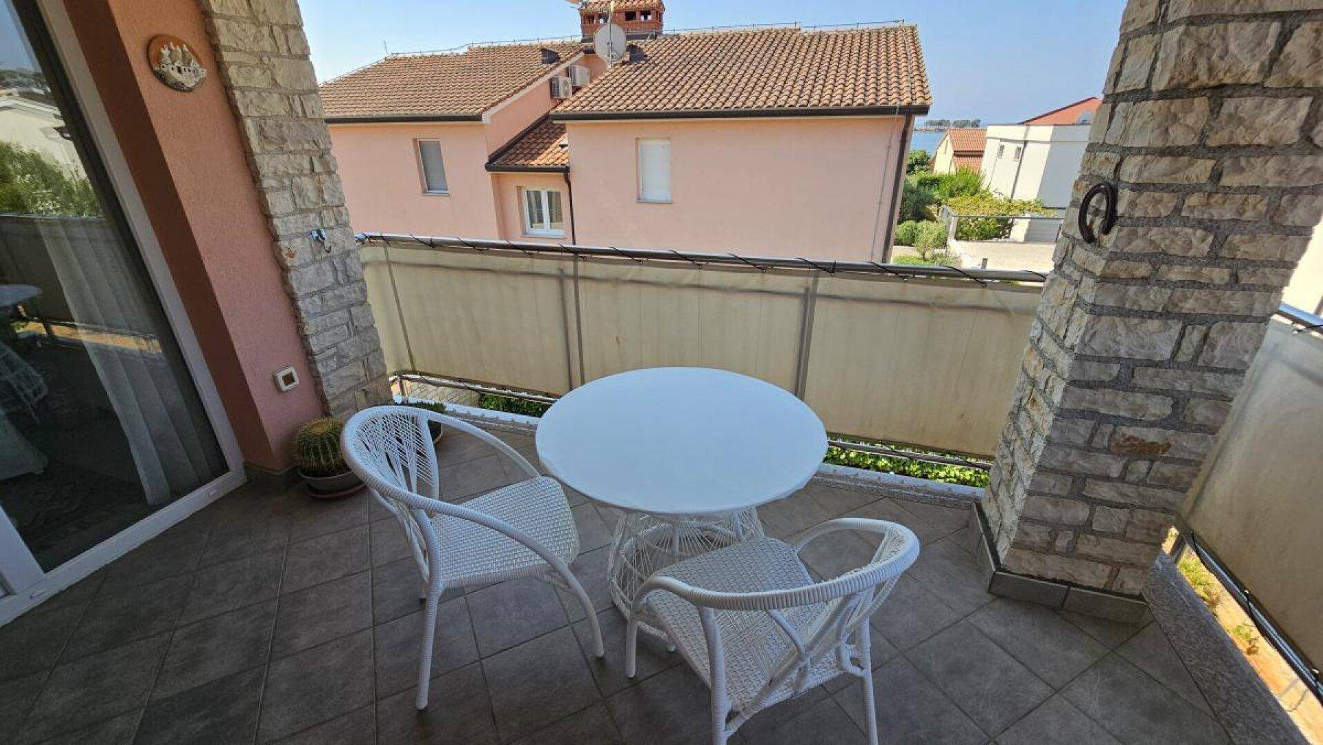 Möblierter Balkon mit Blick auf die Nachbarschaft und das Wasser in der Ferne.