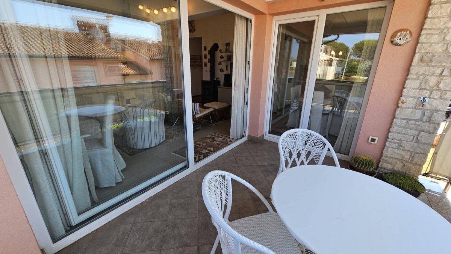 Heller Balkon mit Sitzgelegenheiten und großen Schiebetüren zum Wohnbereich.