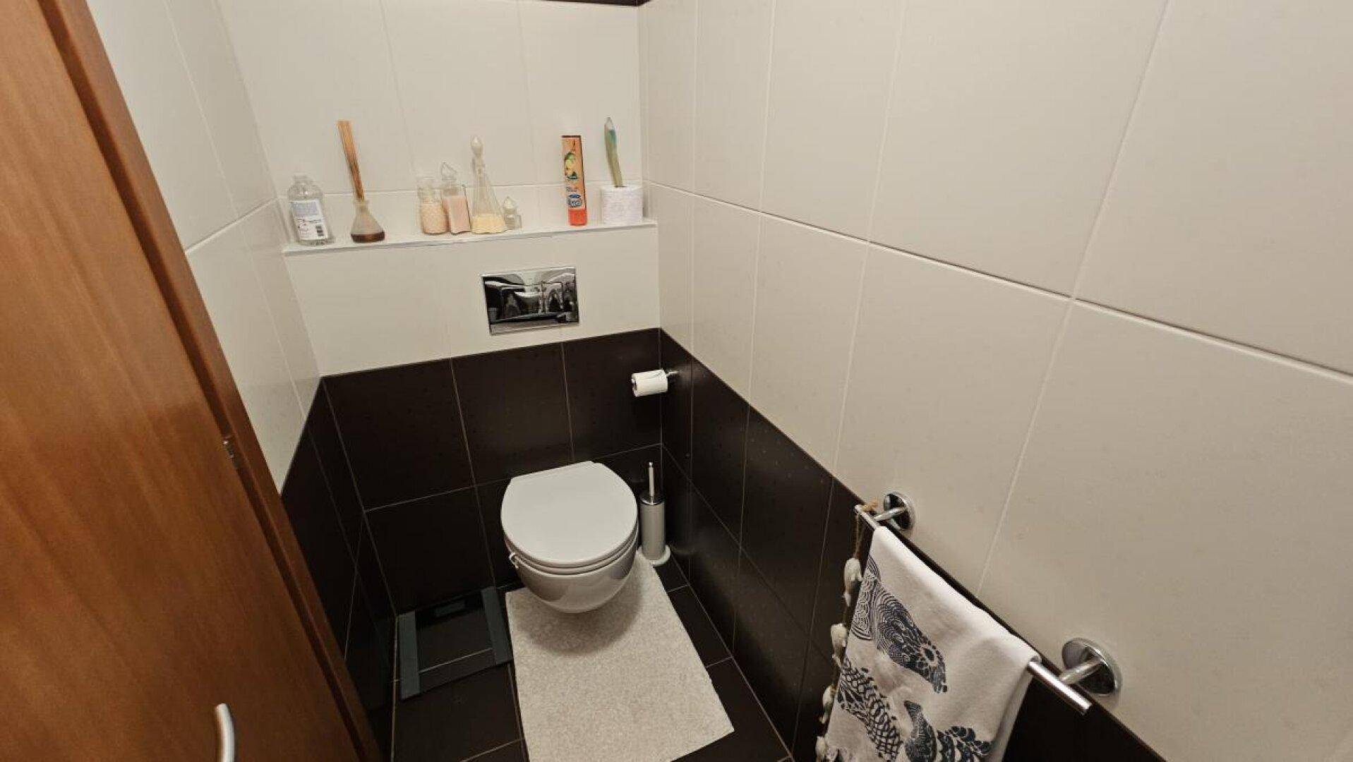 Gäste-WC mit Wand-WC und zweifarbigen Fliesen, praktisch und funktional gestaltet.