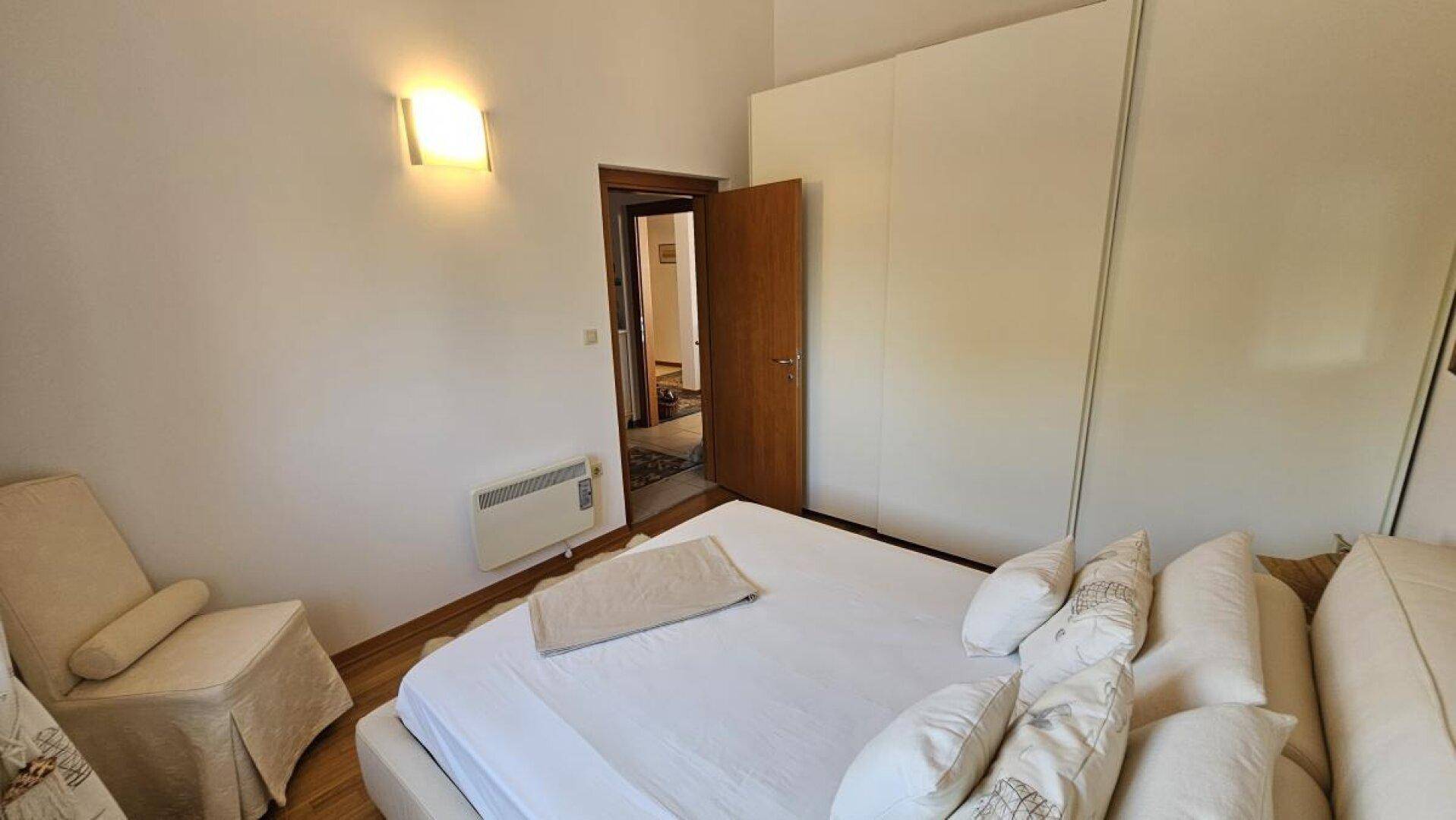 Schlafzimmer mit Doppelbett, großem Kleiderschrank und Heizkörper, mit Holzboden.