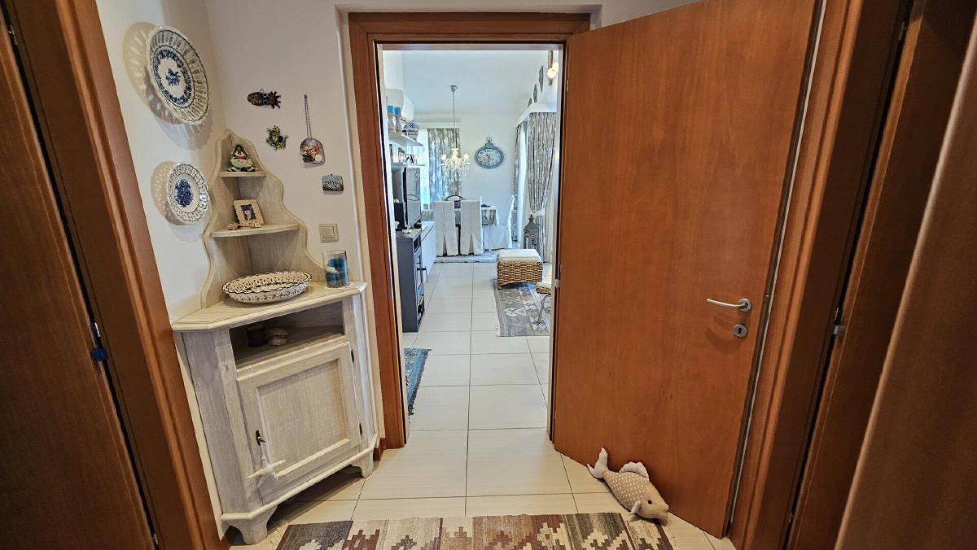 Eingangsbereich mit Eckschrank und Dekoration, führt in den offenen Wohnbereich.