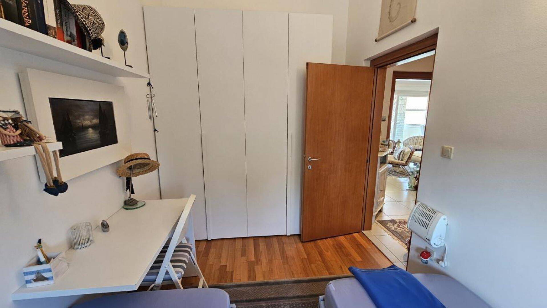 Schlafzimmer mit zwei Einzelbetten, großem Kleiderschrank und Heizkörper, mit Holzboden.
