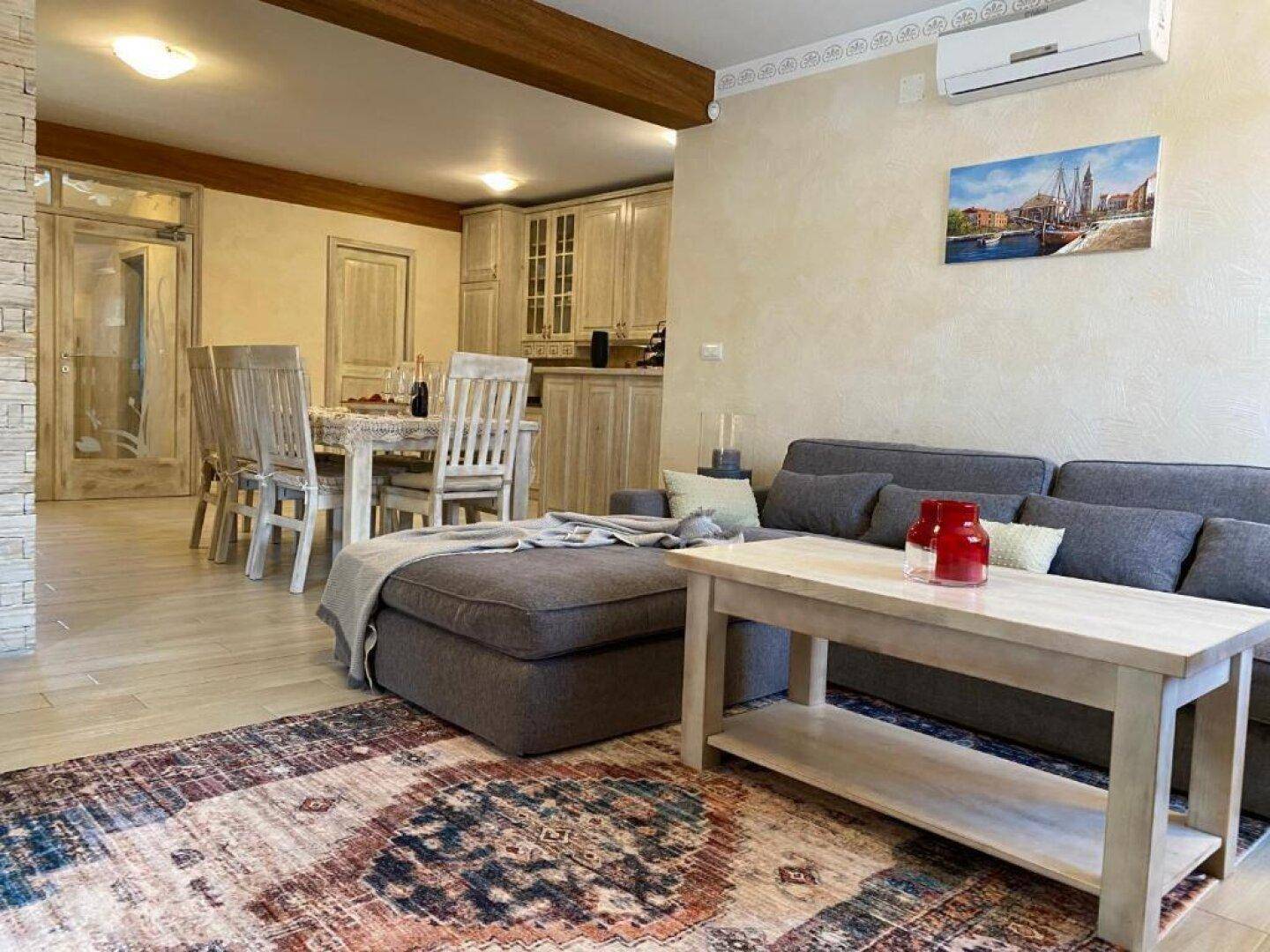 Offener Wohn- und Essbereich mit bequemer Couch, Esstisch und Holzbalken an der Decke.