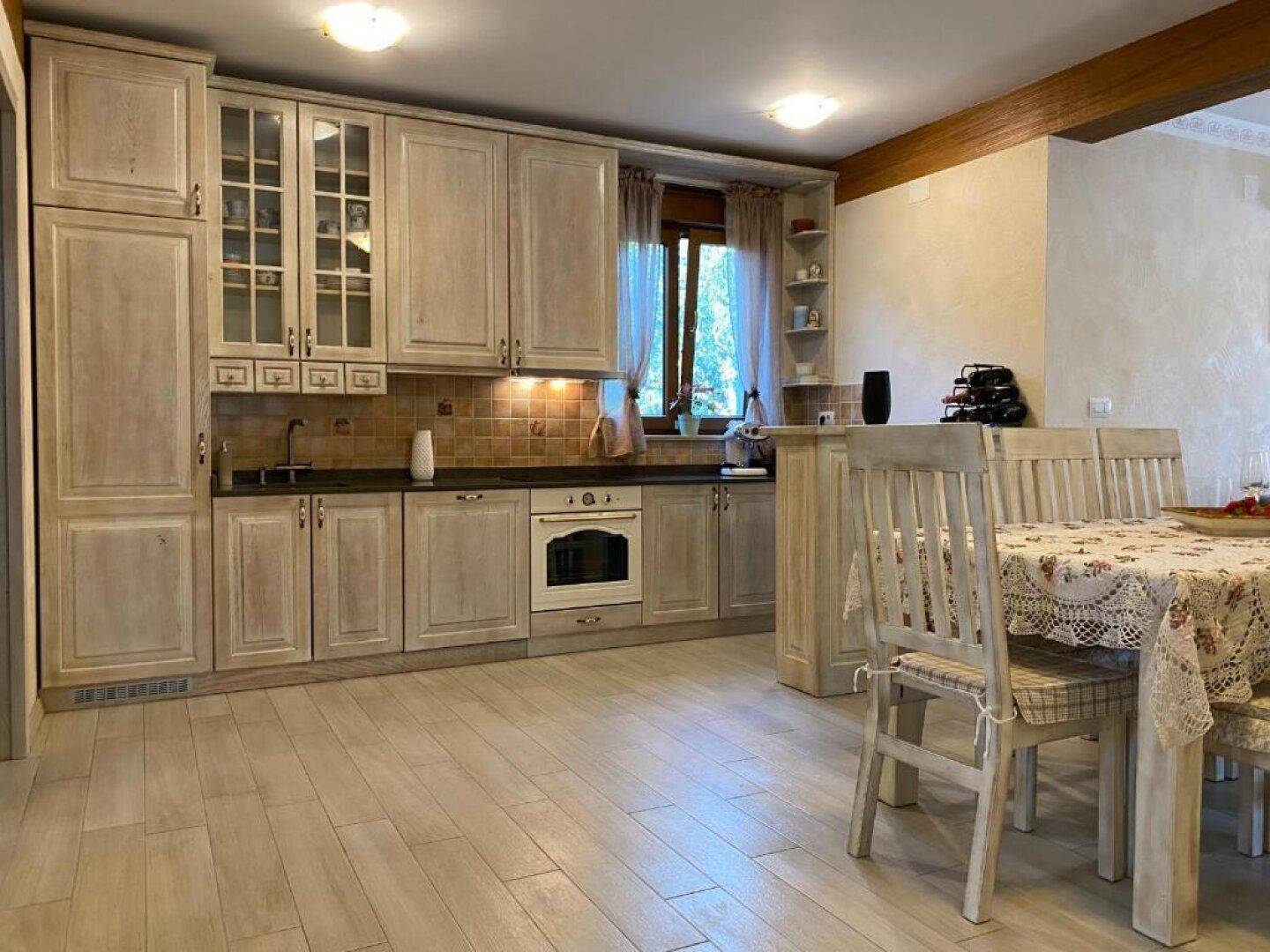 Traditionelle Küche mit hellen Holzschränken, integriertem Backofen und Essbereich.