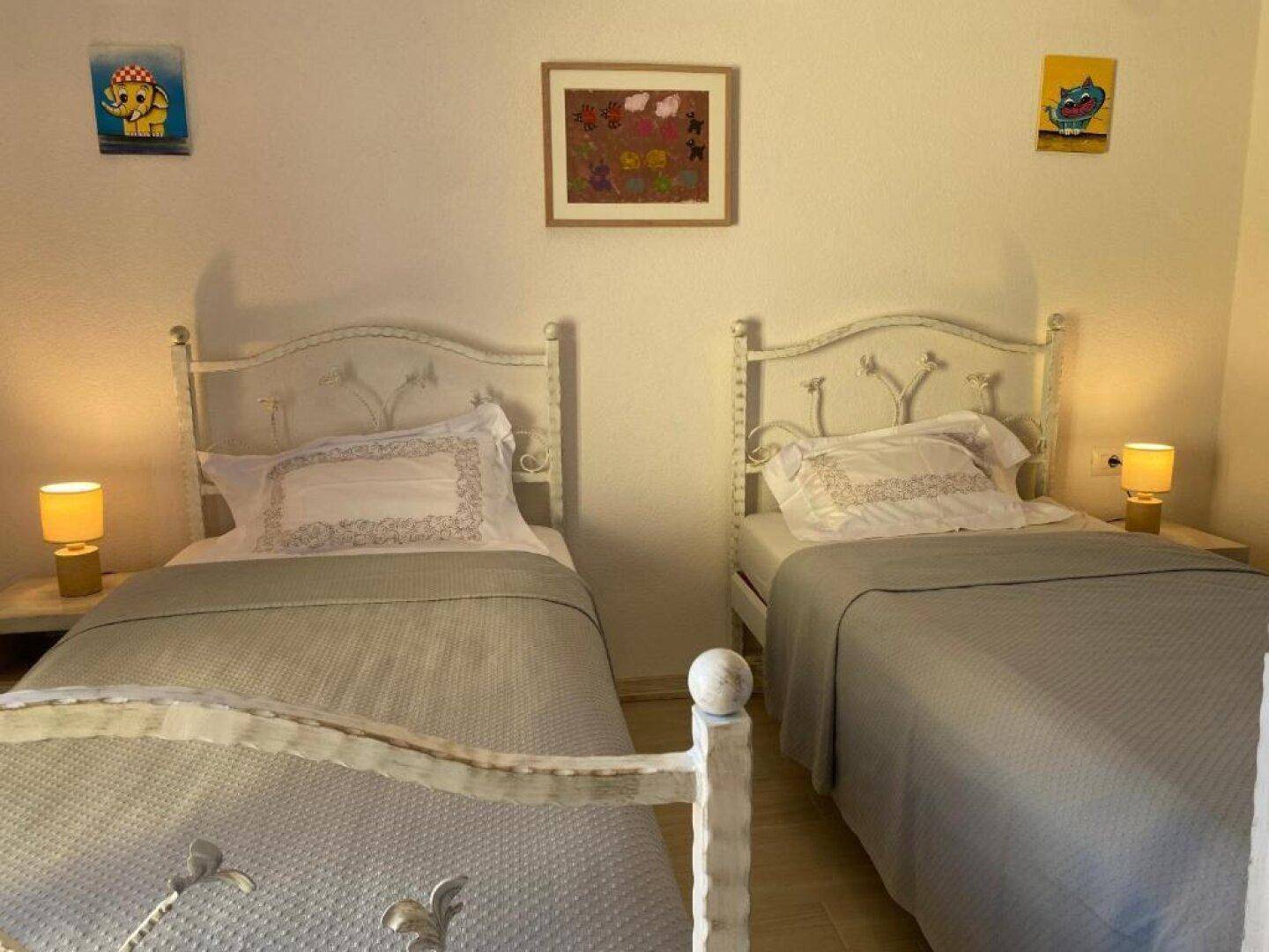 Kinderzimmer mit zwei Einzelbetten, Nachttischen und farbenfrohen Wanddekorationen.