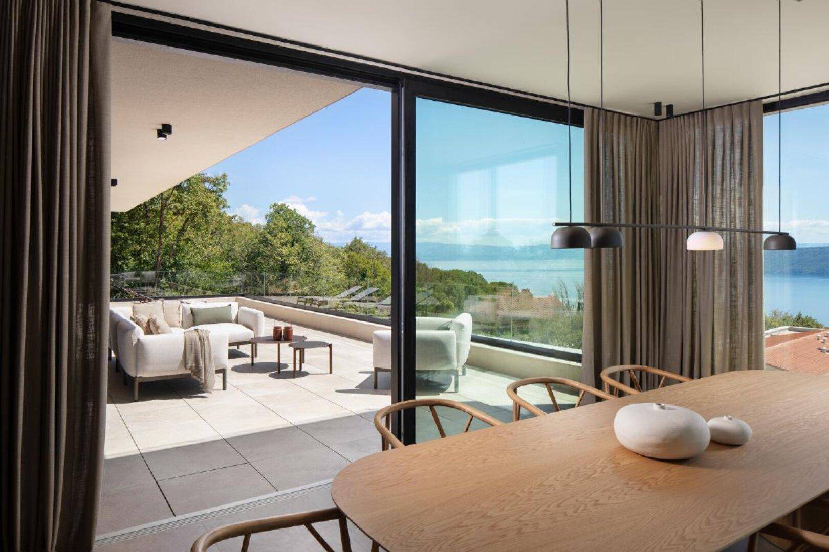 Eleganter Essbereich mit Holztisch und Stühlen, direktem Zugang zur Terrasse und Meerblick.
