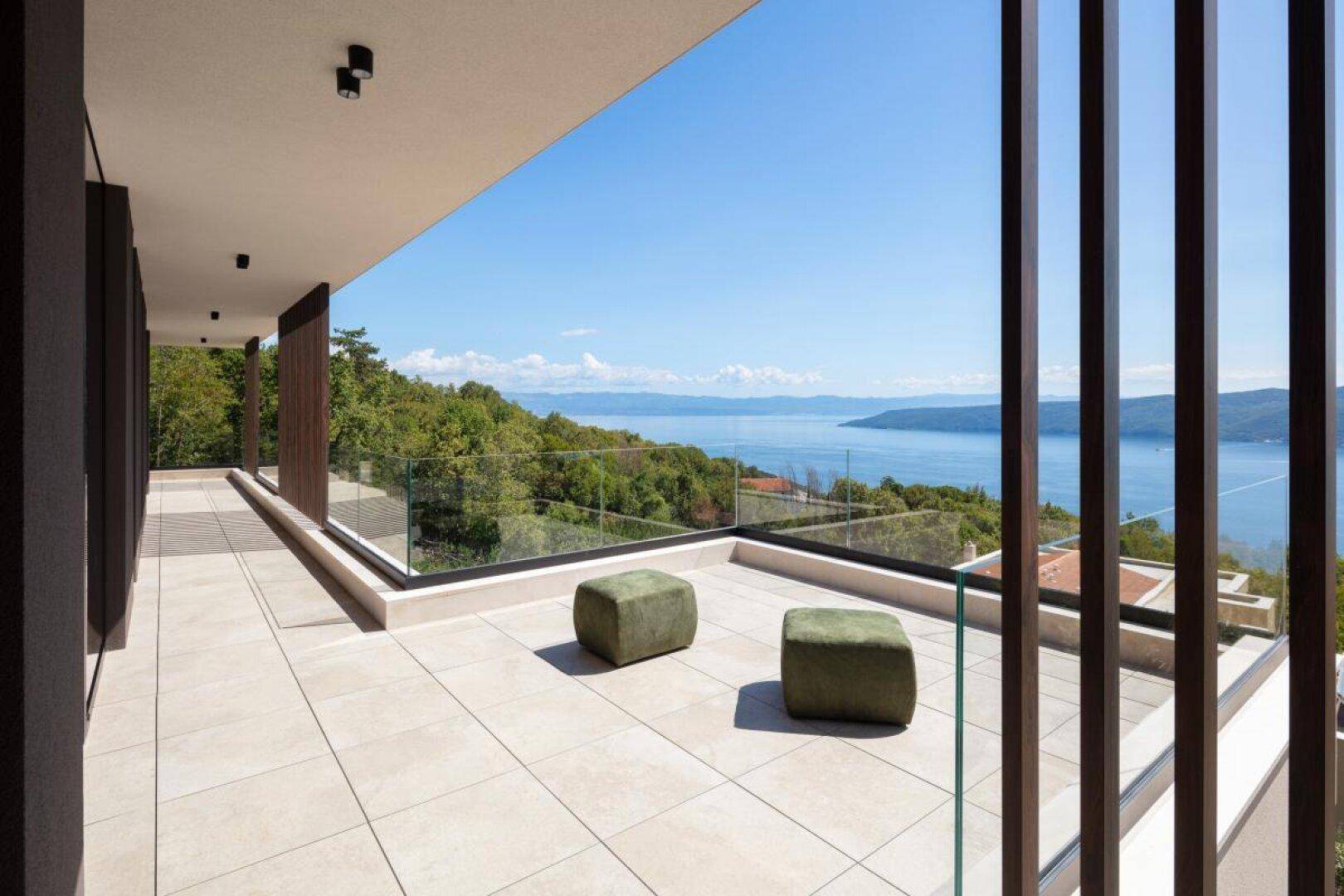 Geräumige Terrasse mit Fliesenboden und Glasgeländer bietet einen weiten Blick auf das Meer.