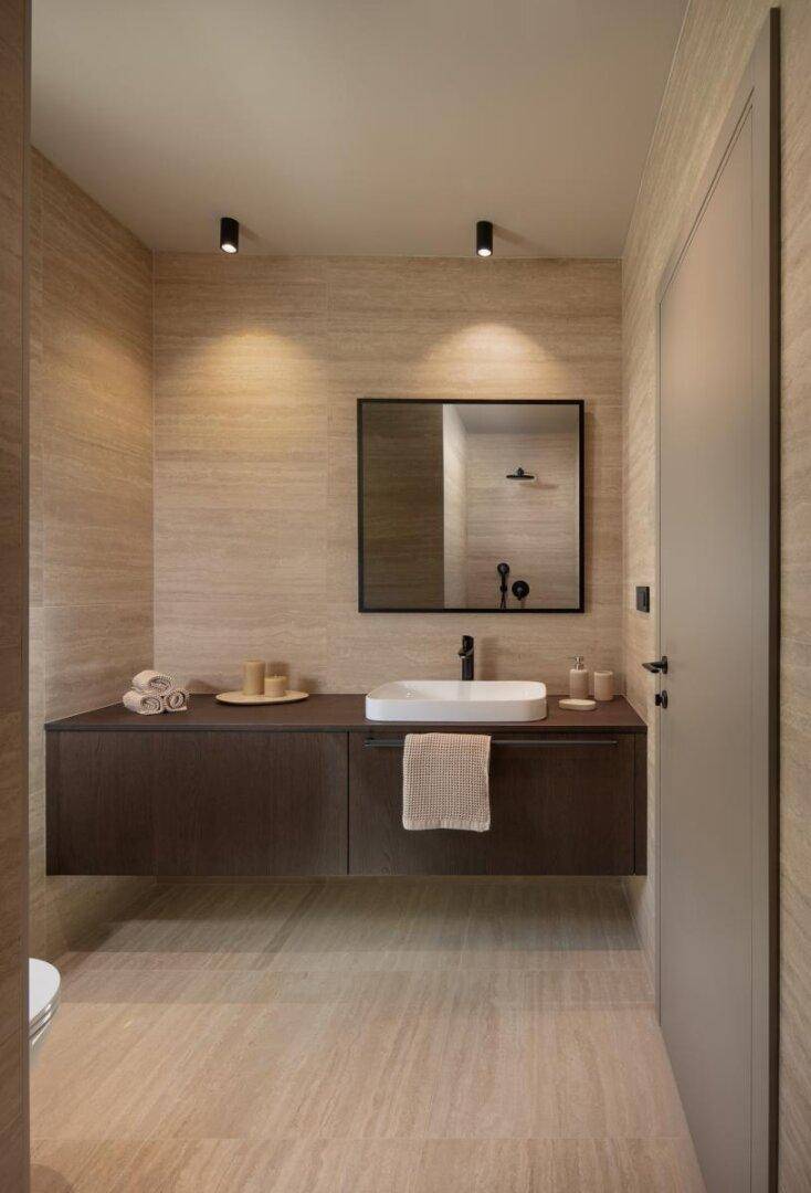Modernes Badezimmer mit schwebendem Waschtisch, großem Spiegel und eleganten Fliesen.