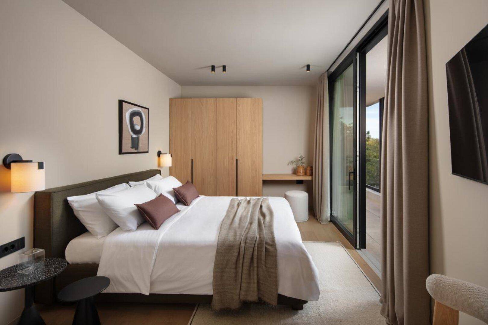 Gemütliches Schlafzimmer mit Holzkleiderschrank, Doppelbett und Zugang zu einem Balkon.