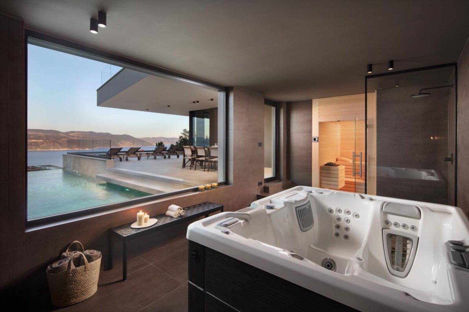 Exklusiver Wellnessbereich mit Whirlpool, Sauna und Panoramafenstern mit Meerblick.