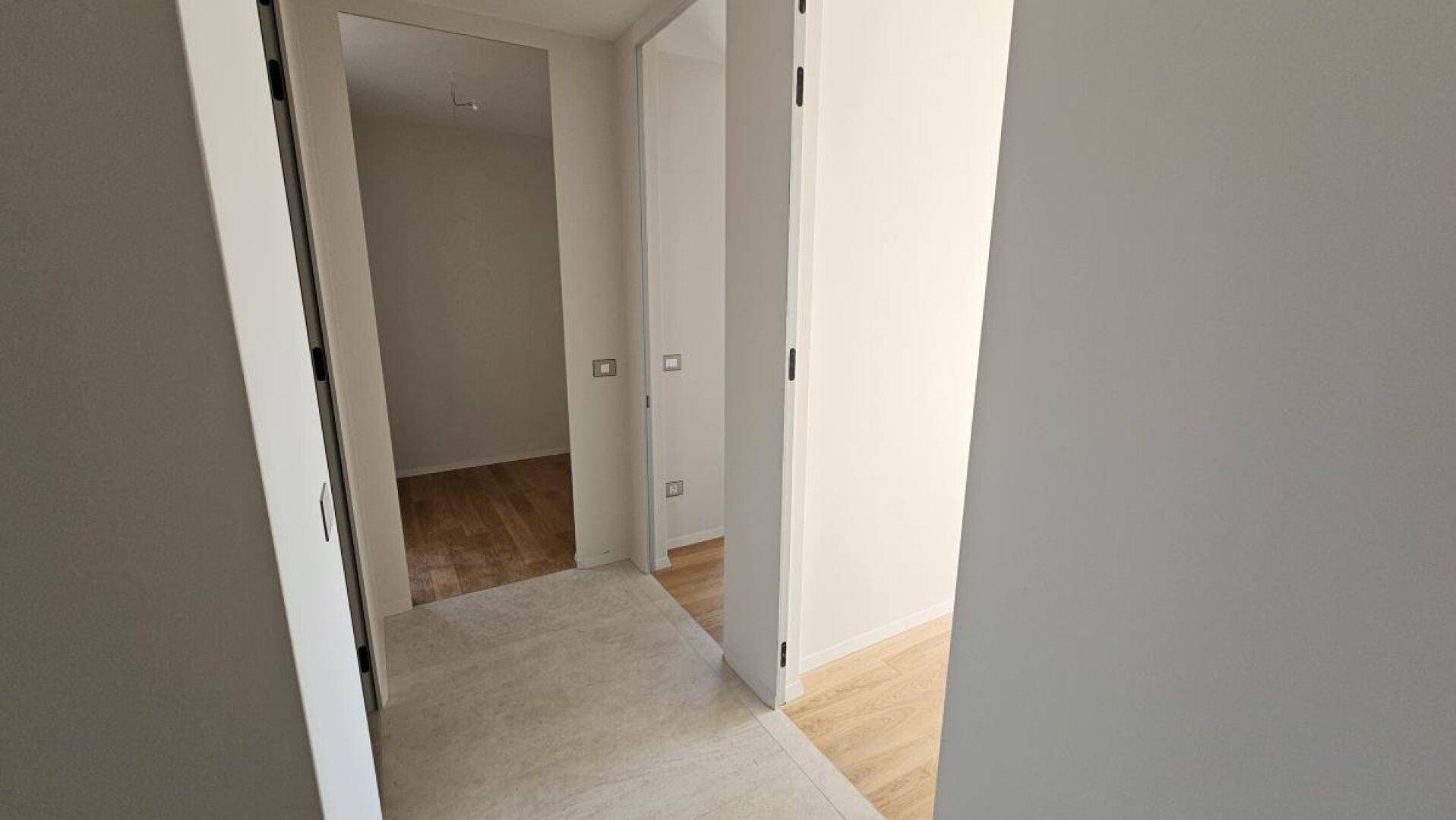 Heller Flur mit offenen Türen zu weiteren Räumen, die mit Holzboden ausgestattet sind.