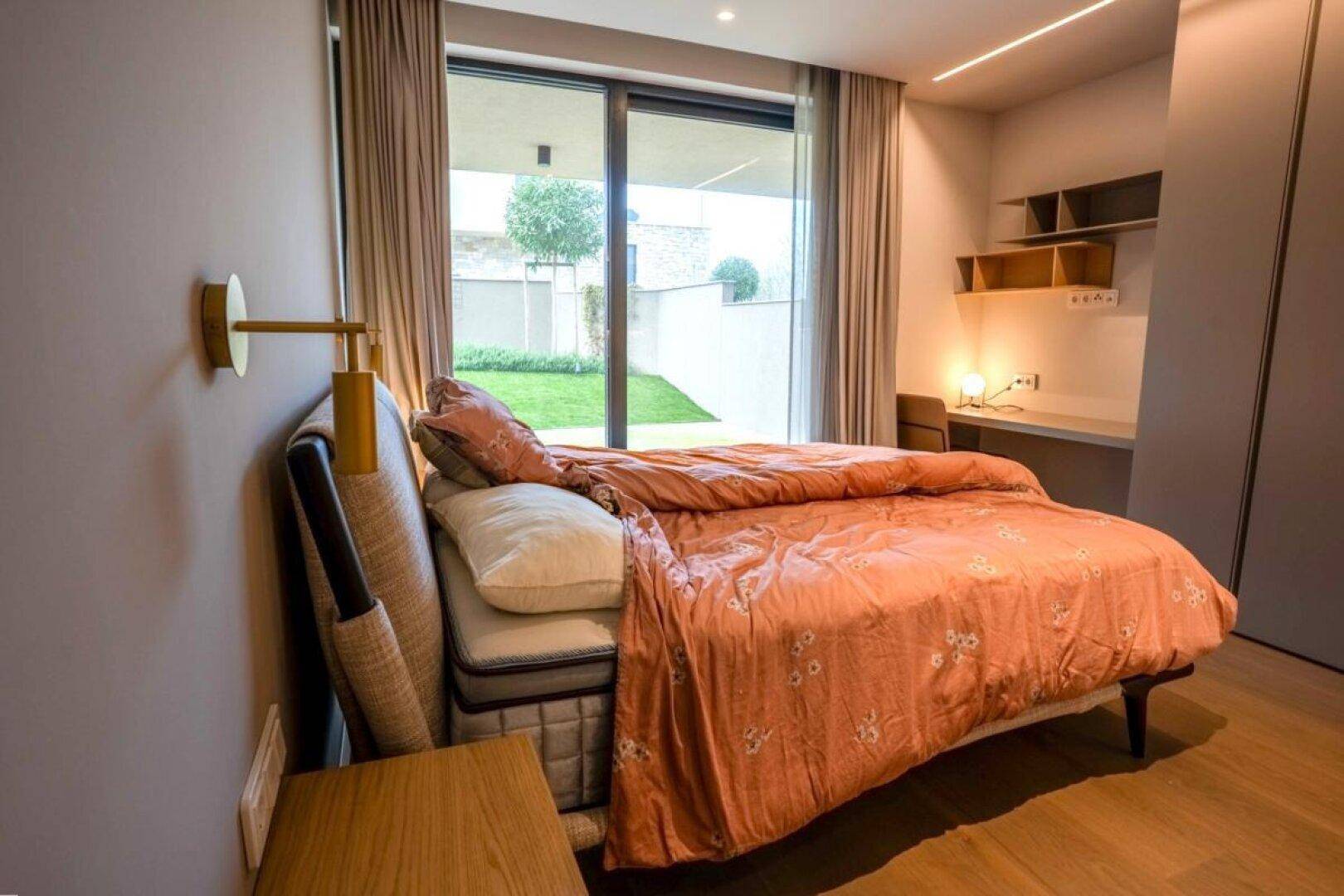 Komfortables Schlafzimmer mit Schreibtisch, Nachttisch und direktem Zugang zum Garten.