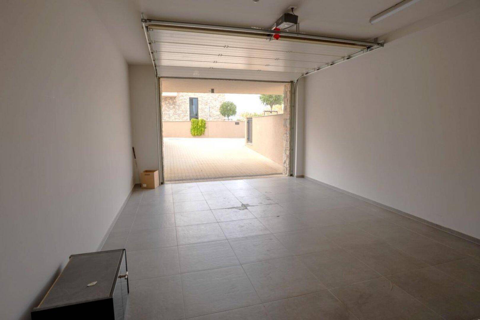 Geräumige Garage mit offenem Tor und direktem Zugang zur gepflasterten Einfahrt.
