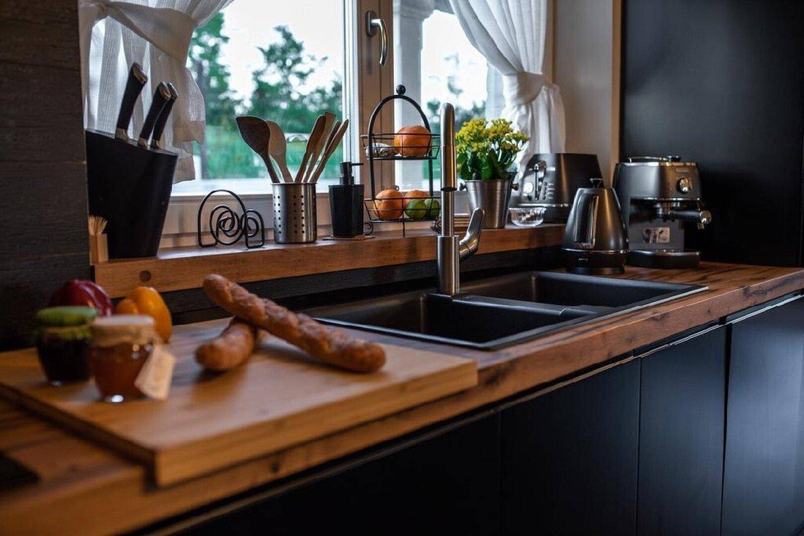 Moderne Küche mit dunklen Schränken, Holzarbeitsplatte und Spülbecken unter einem Fenster.