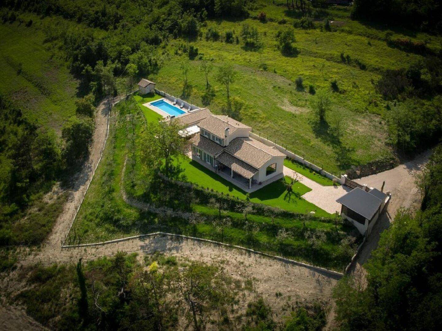 Luftaufnahme der Villa mit Pool, umgeben von üppiger grüner Natur und einem weitläufigen Grundstück.