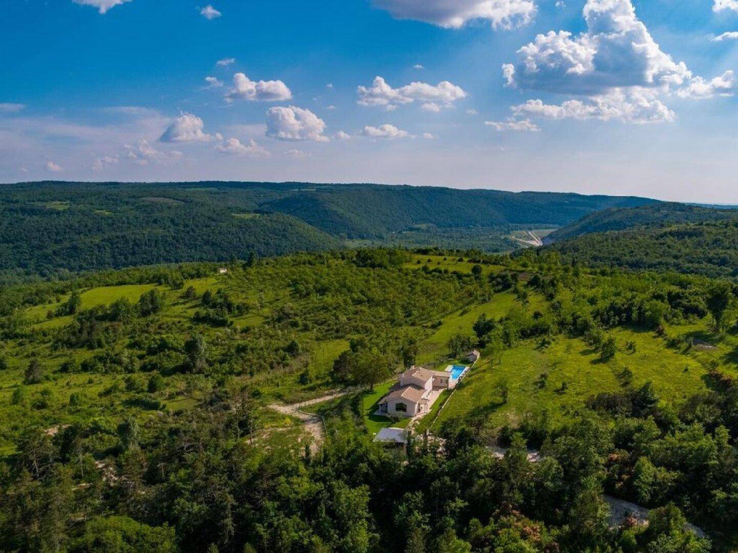 Panoramische Luftaufnahme der Villa, eingebettet in eine ausgedehnte, hügelige und bewaldete Landschaft.