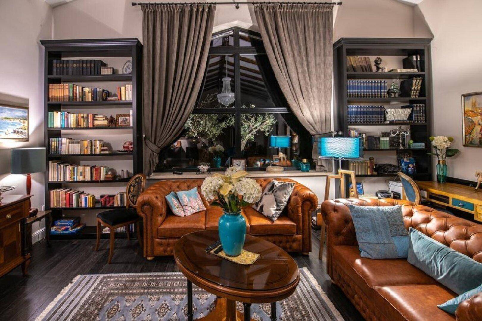 Helles Wohnzimmer mit Ledersofas, Bücherregalen und großen Fenstern, die den Raum lichtdurchfluten.