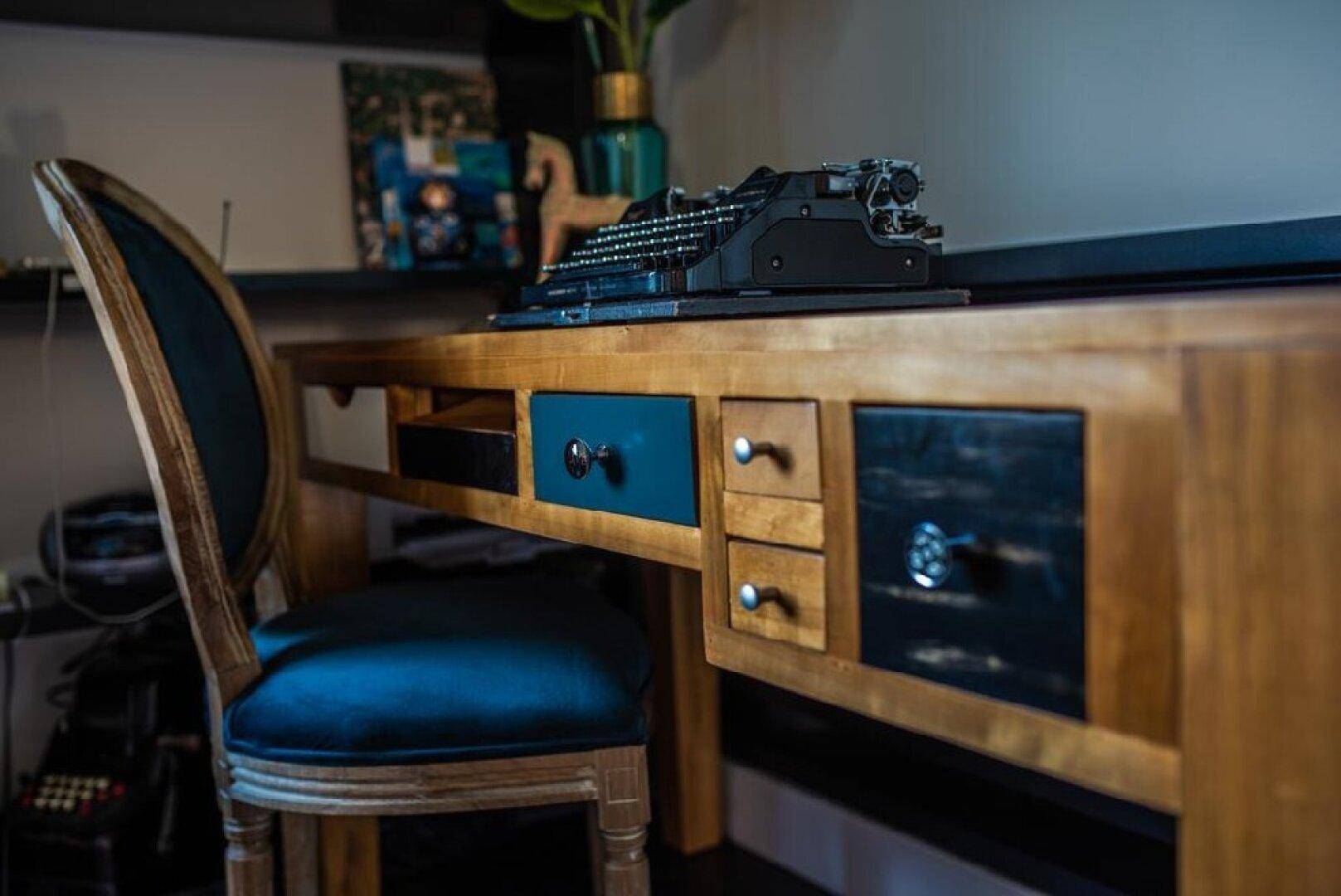 Detailaufnahme eines Holzschreibtisches mit Schubladen und einer klassischen Schreibmaschine.