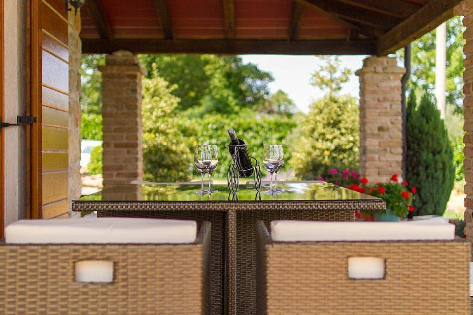 Nahaufnahme des eleganten Outdoor-Loungebereichs mit Rattanmöbeln und Blick ins Grüne.