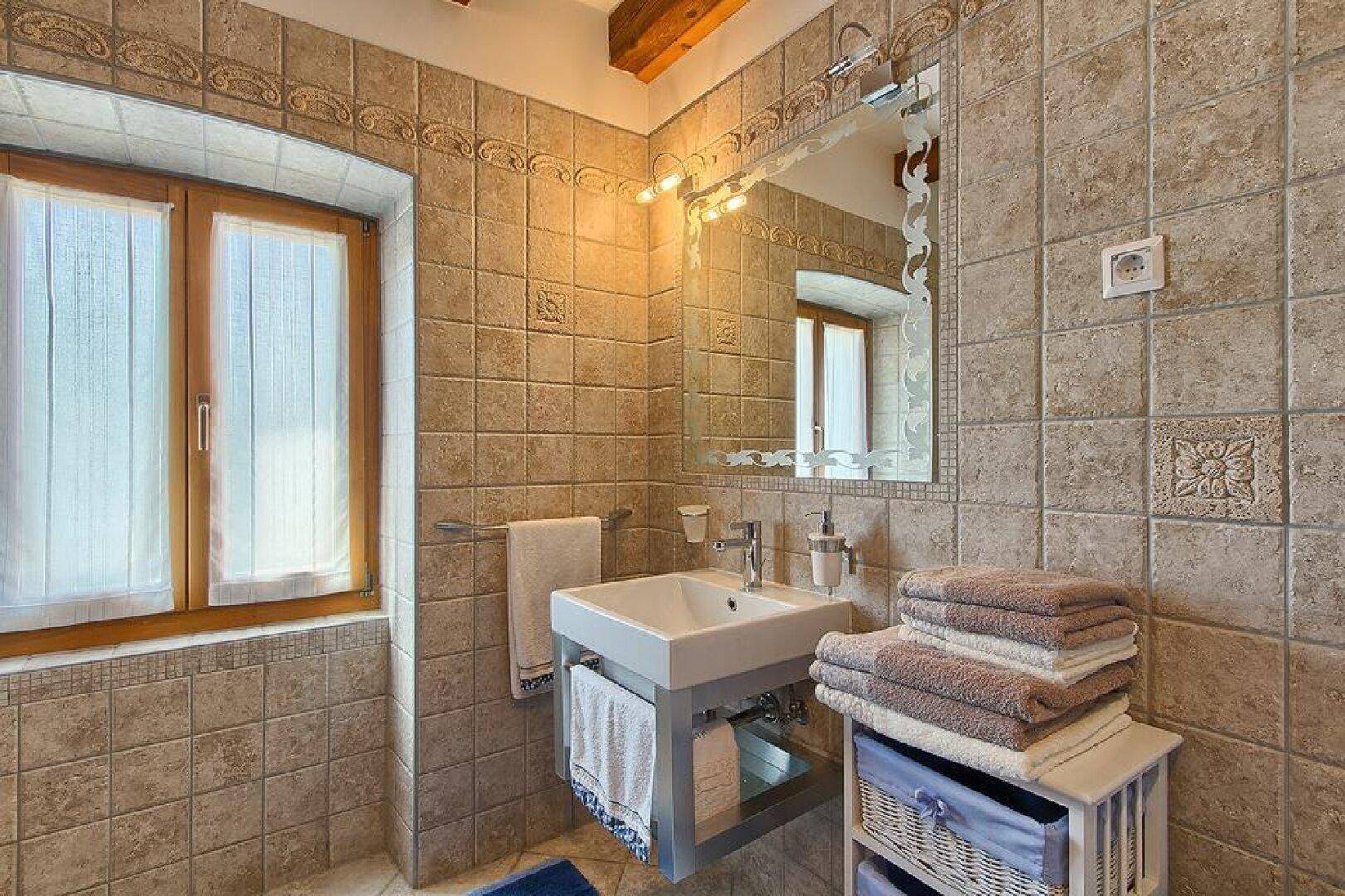 Traditionelles Badezimmer mit beigefarbenen Fliesen, modernem Waschbecken und Fenster für Tageslicht.