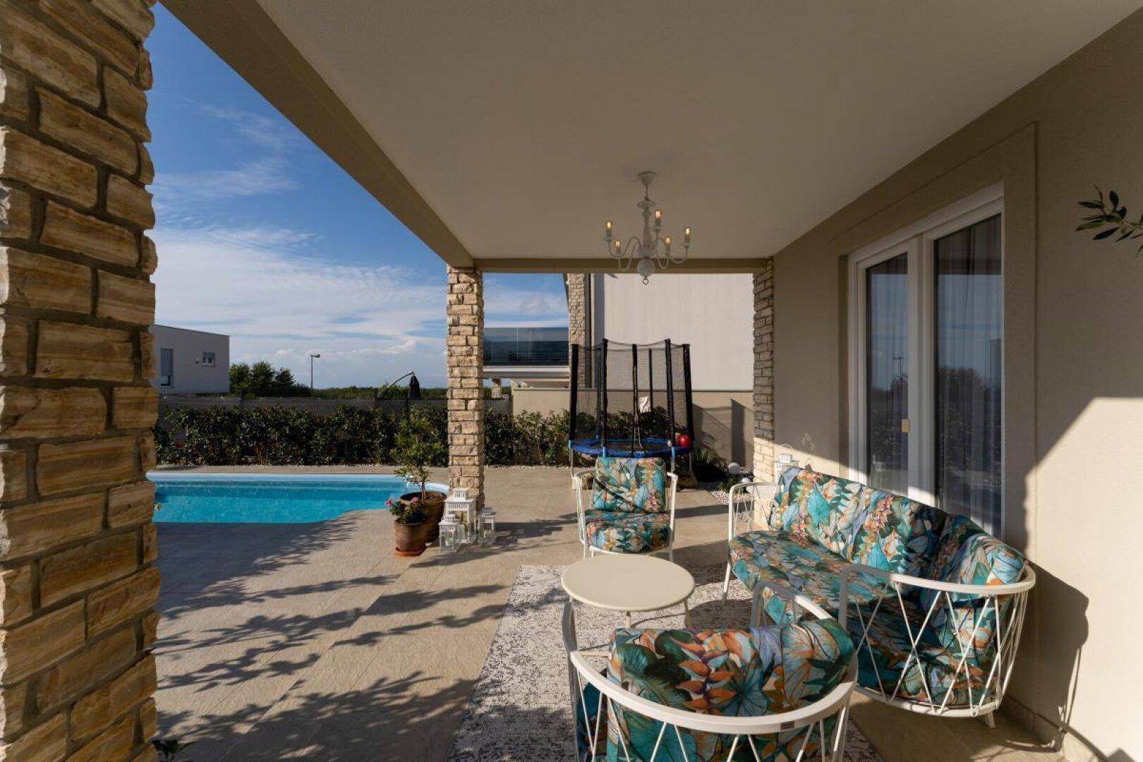 Gemütliche überdachte Terrasse mit Lounge-Möbeln und direktem Zugang zum Pool.