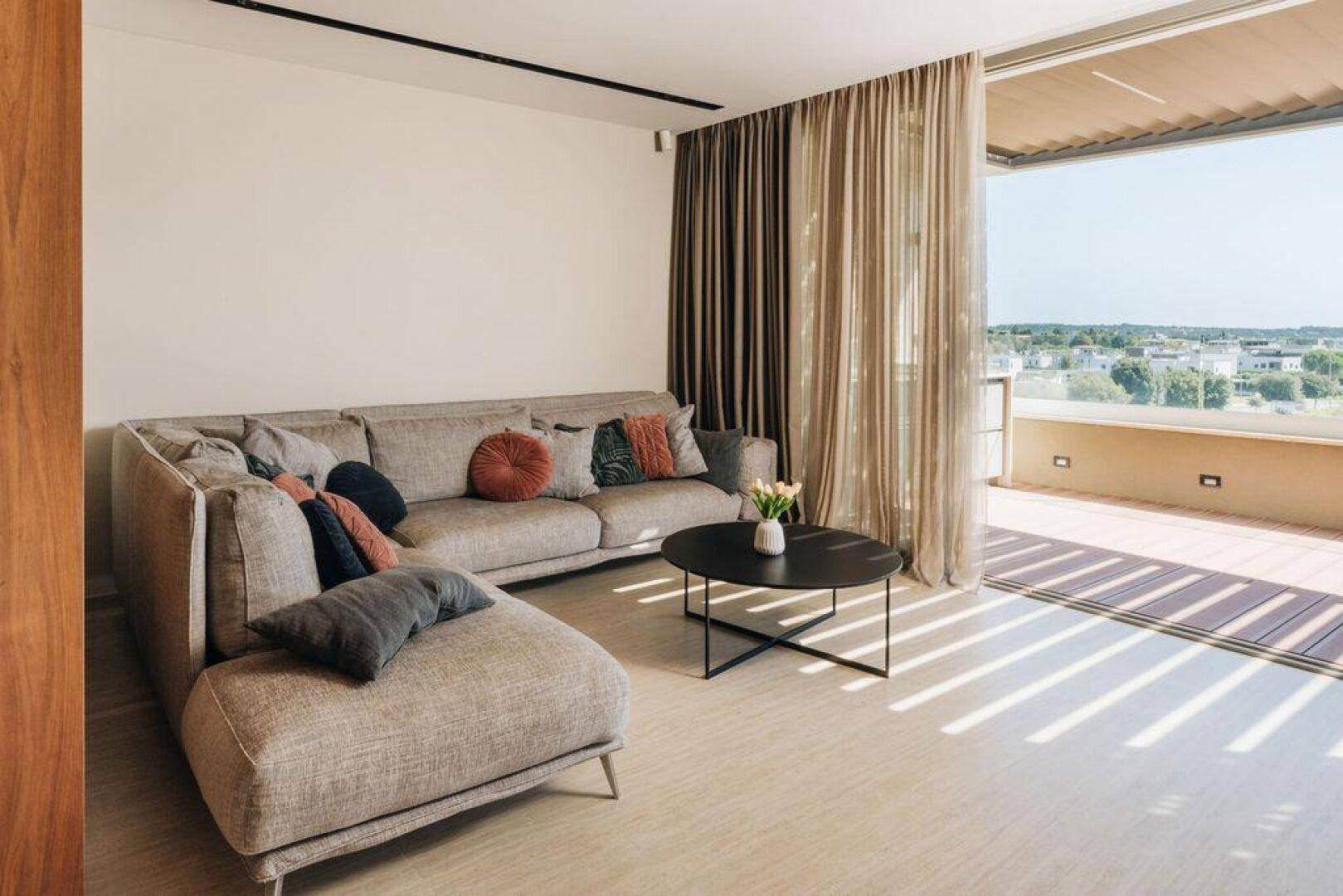 Gemütliches Wohnzimmer mit großem Ecksofa, Couchtisch und direktem Zugang zur Außenterrasse.