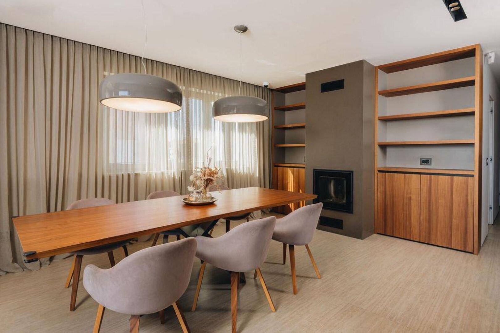 Eleganter Essbereich mit Holztisch, bequemen Stühlen, Kamin und integrierten Regalen.