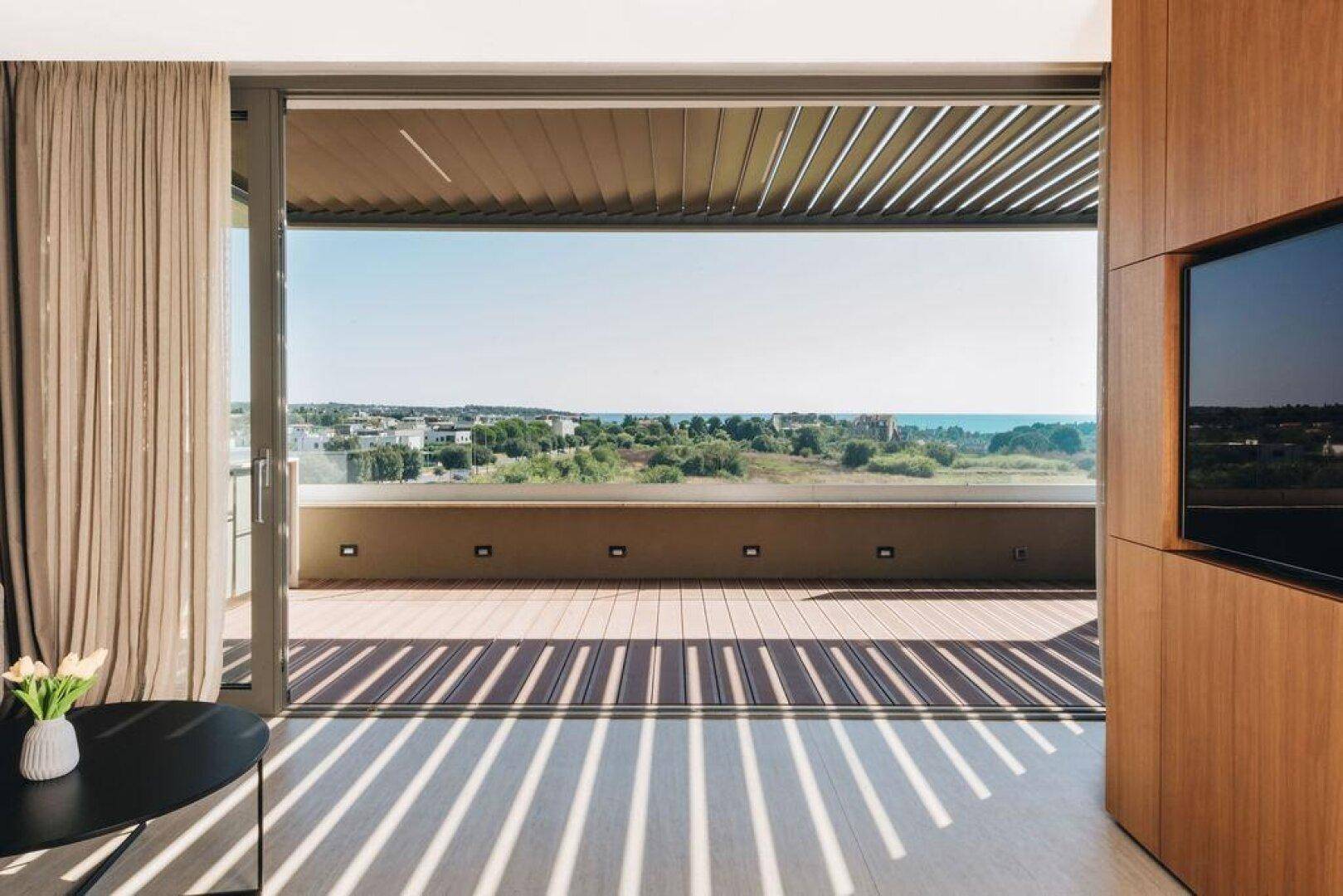 Heller Wohnbereich mit Blick auf eine sonnige Terrasse und die umliegende Landschaft.