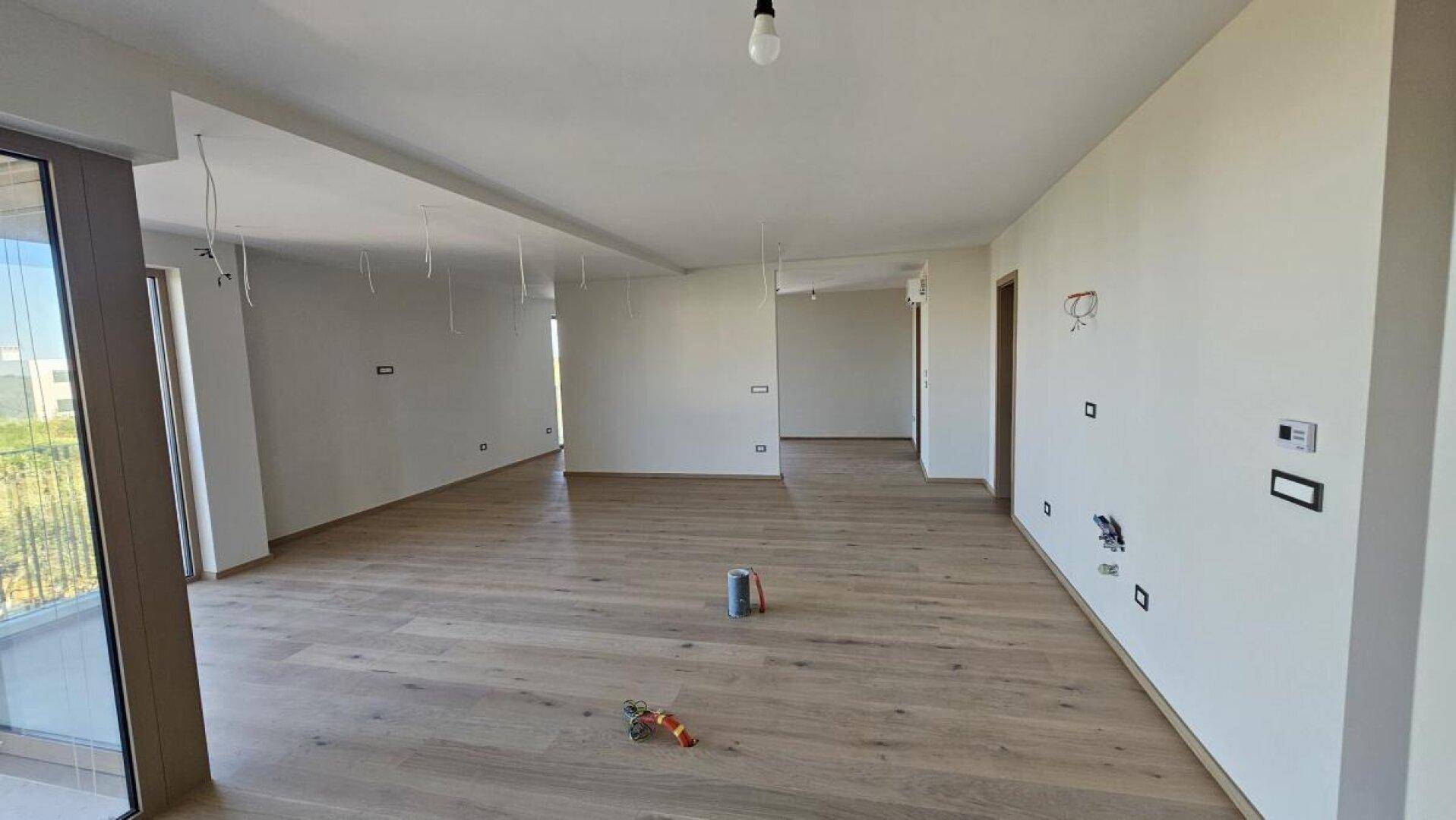 Geräumiger, unmöblierter Wohnbereich mit hellem Holzboden und weißen Wänden.