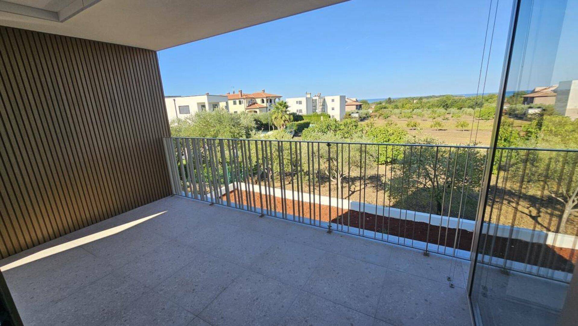 Geräumiger Balkon mit Fliesenboden und weitem Blick über die Landschaft bis zum Meer.