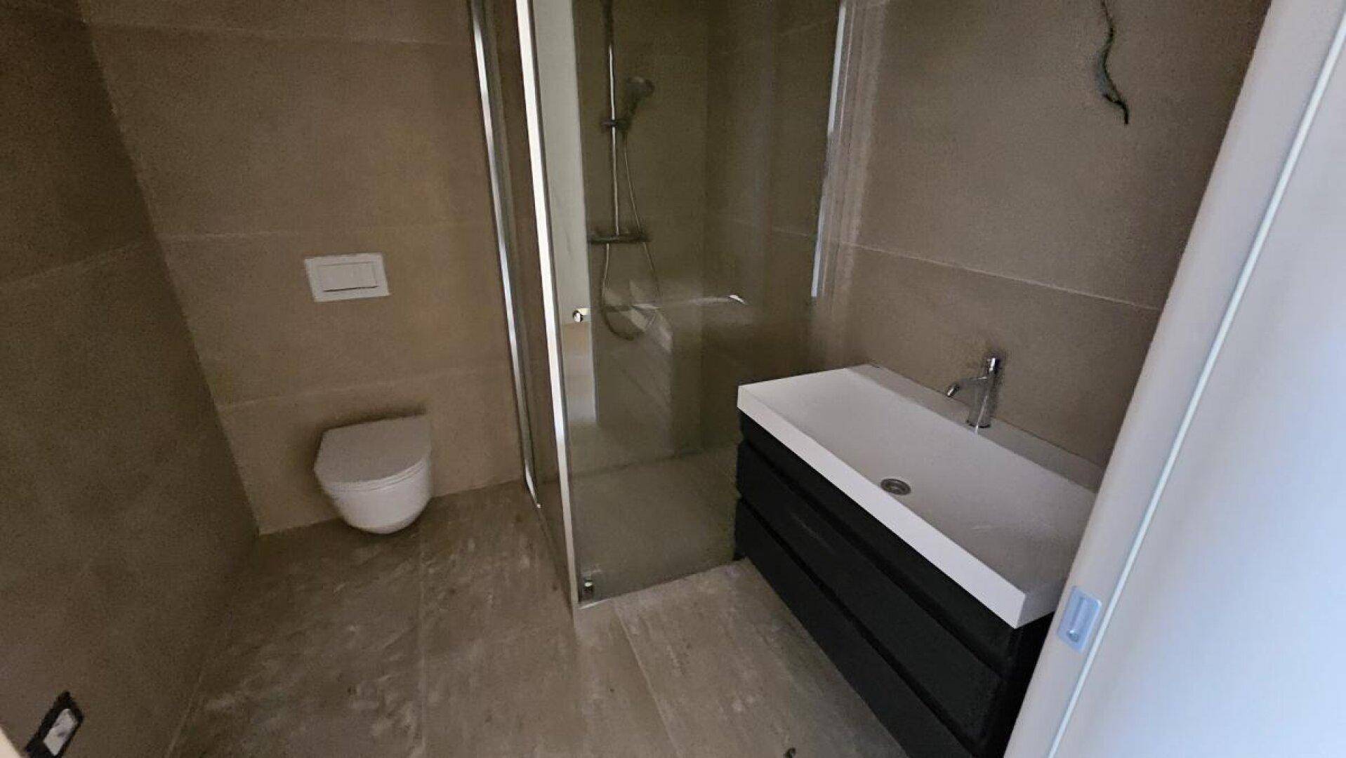Modernes Badezimmer mit Dusche, wandhängender Toilette und stilvollem Waschtisch.
