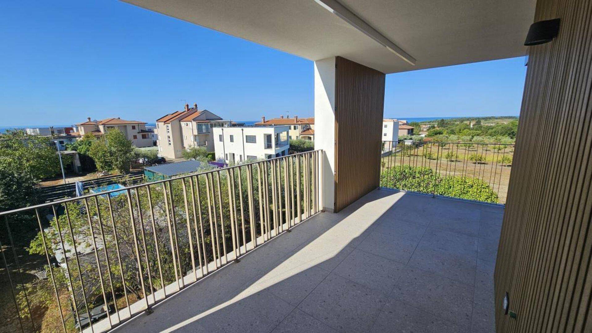 Geräumiger Balkon mit Meerblick und Aussicht auf die umliegende Wohngegend und viel Grün.