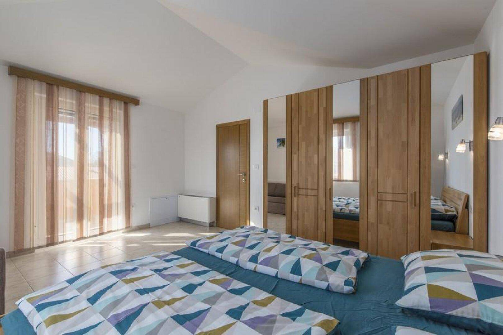 Helles Schlafzimmer mit Doppelbett und großen Spiegelschränken, die den Raum optisch vergrößern.