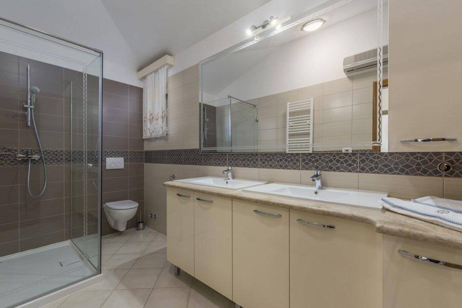 Modernes Badezimmer mit Doppelwaschbecken, großer Spiegelfläche und ebenerdiger Dusche.