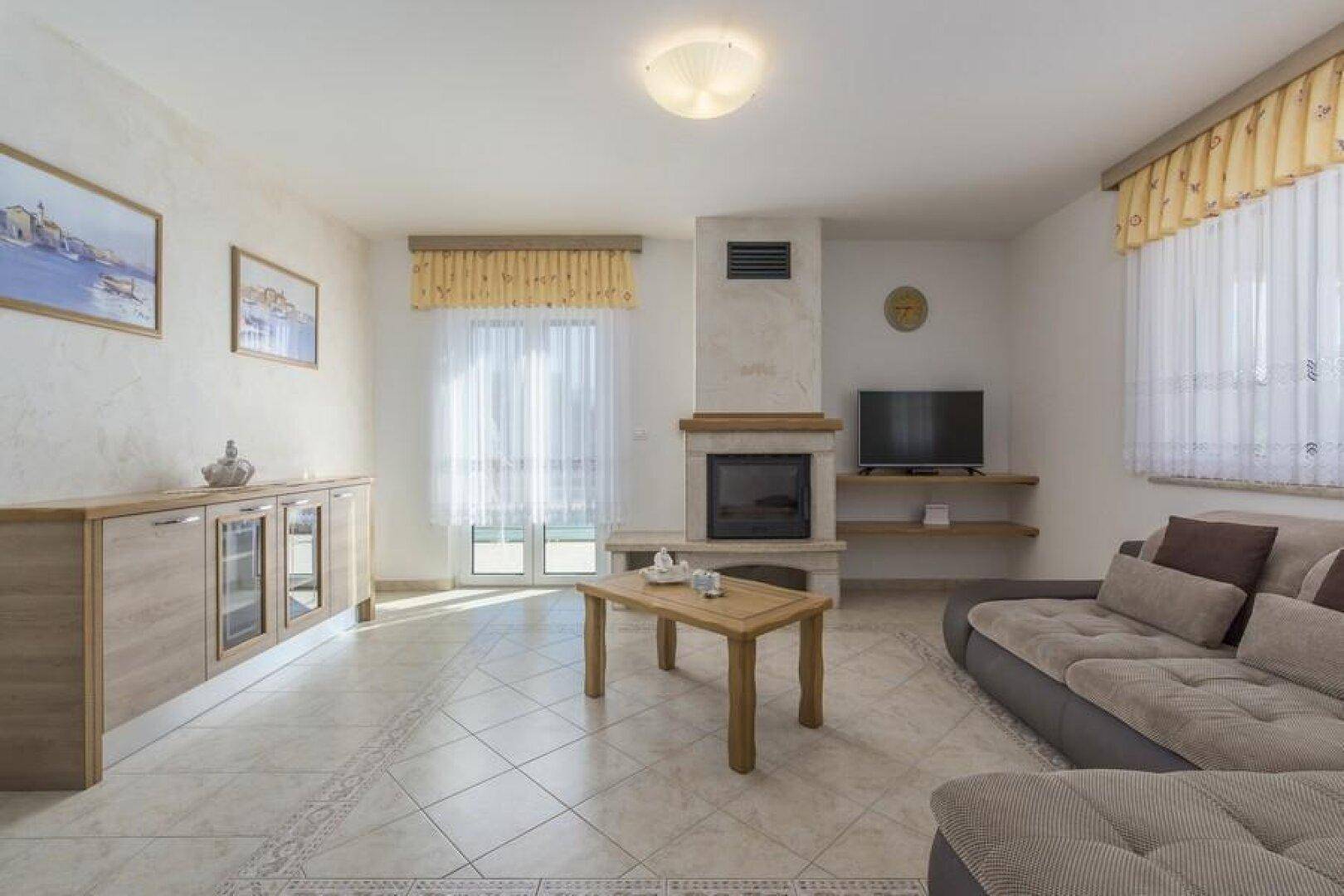 Helles Wohnzimmer mit bequemer Sitzecke, Kamin und Zugang zur Terrasse.